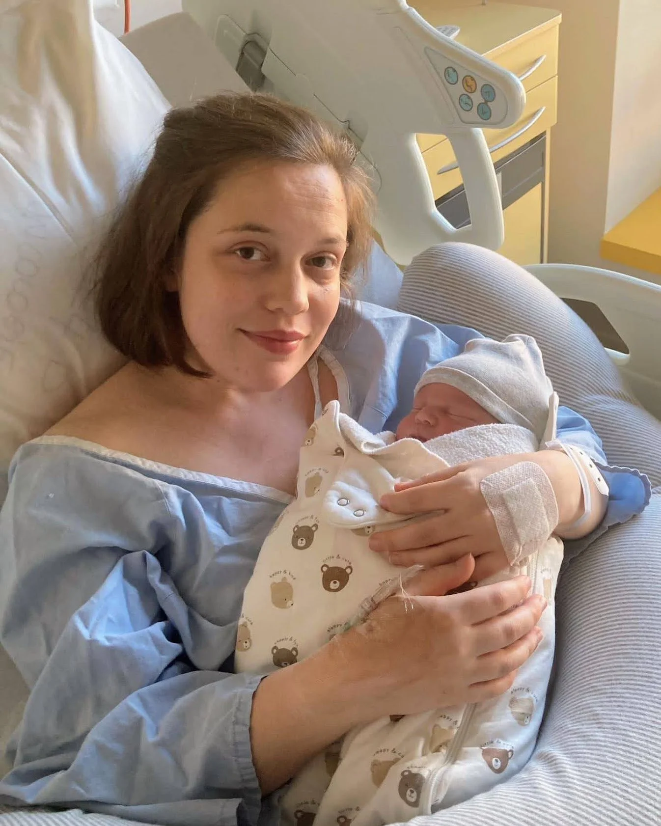 new mother with newborn smiling in hospital bed