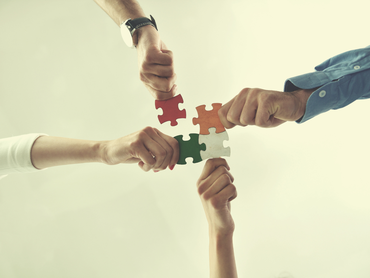 People holding puzzle pieces to demonstrate working together.