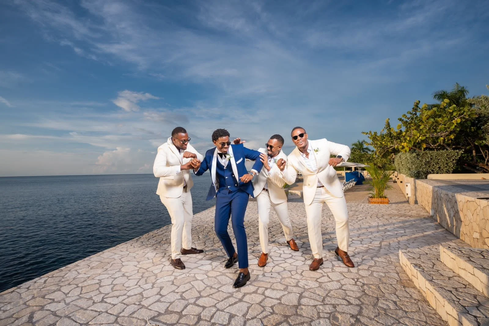 Group of five men in suits dancing and having fun by the waterfront.