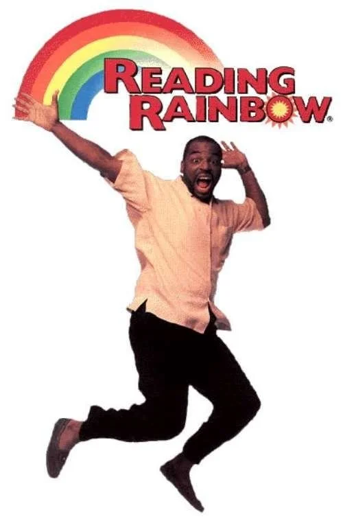 A man with a beard jumping with an excited expression in front of a rainbow and the words 'Reading Rainbow'