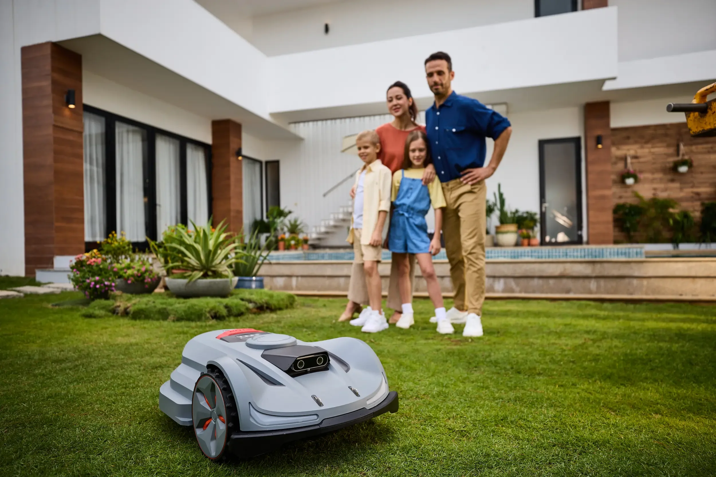 Sunseeker X Series robotic mower on a residential lawn with homeowners nearby