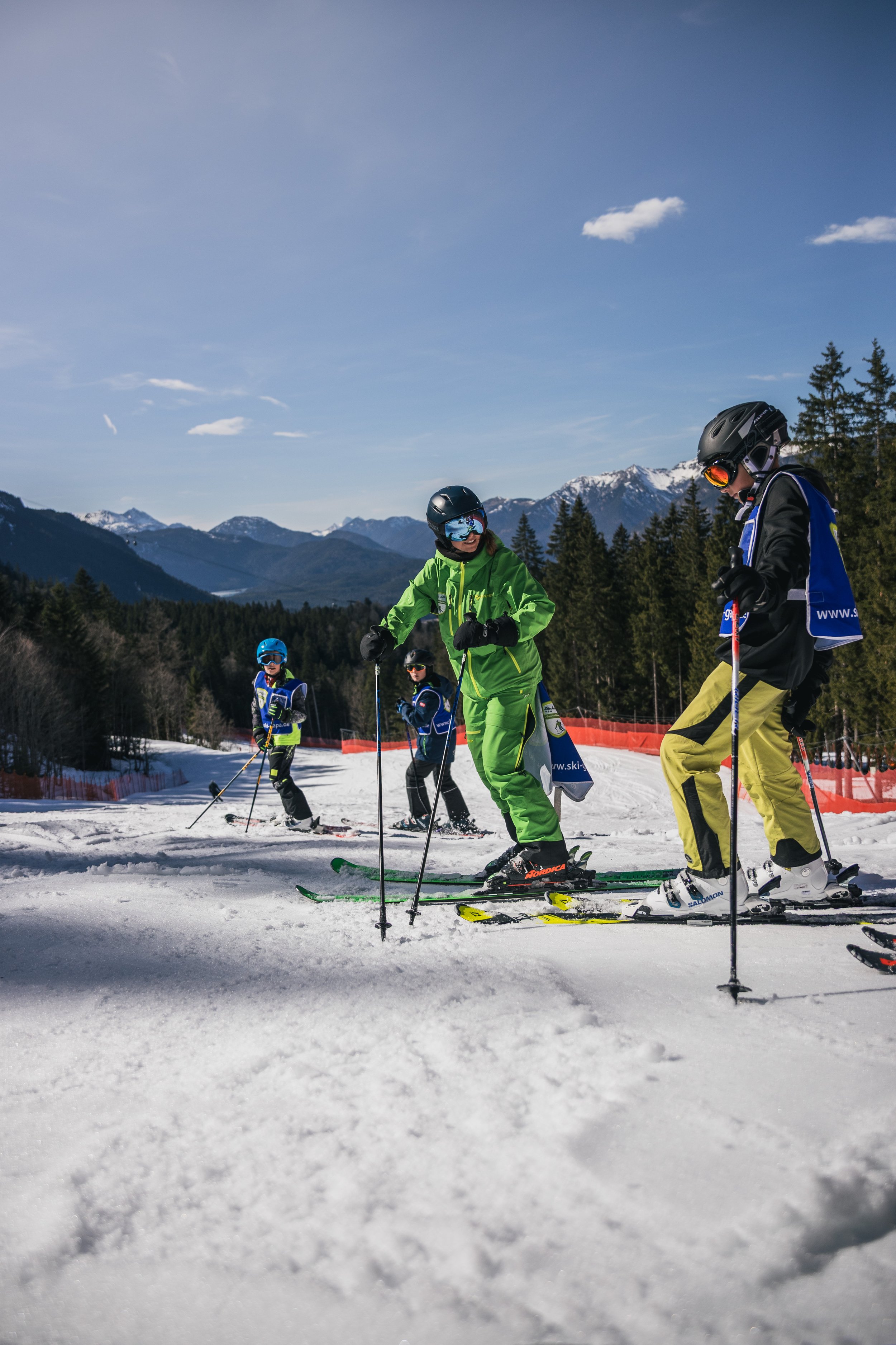 Kids skiing on snow-covered slopes with mountainous landscape in the background.
