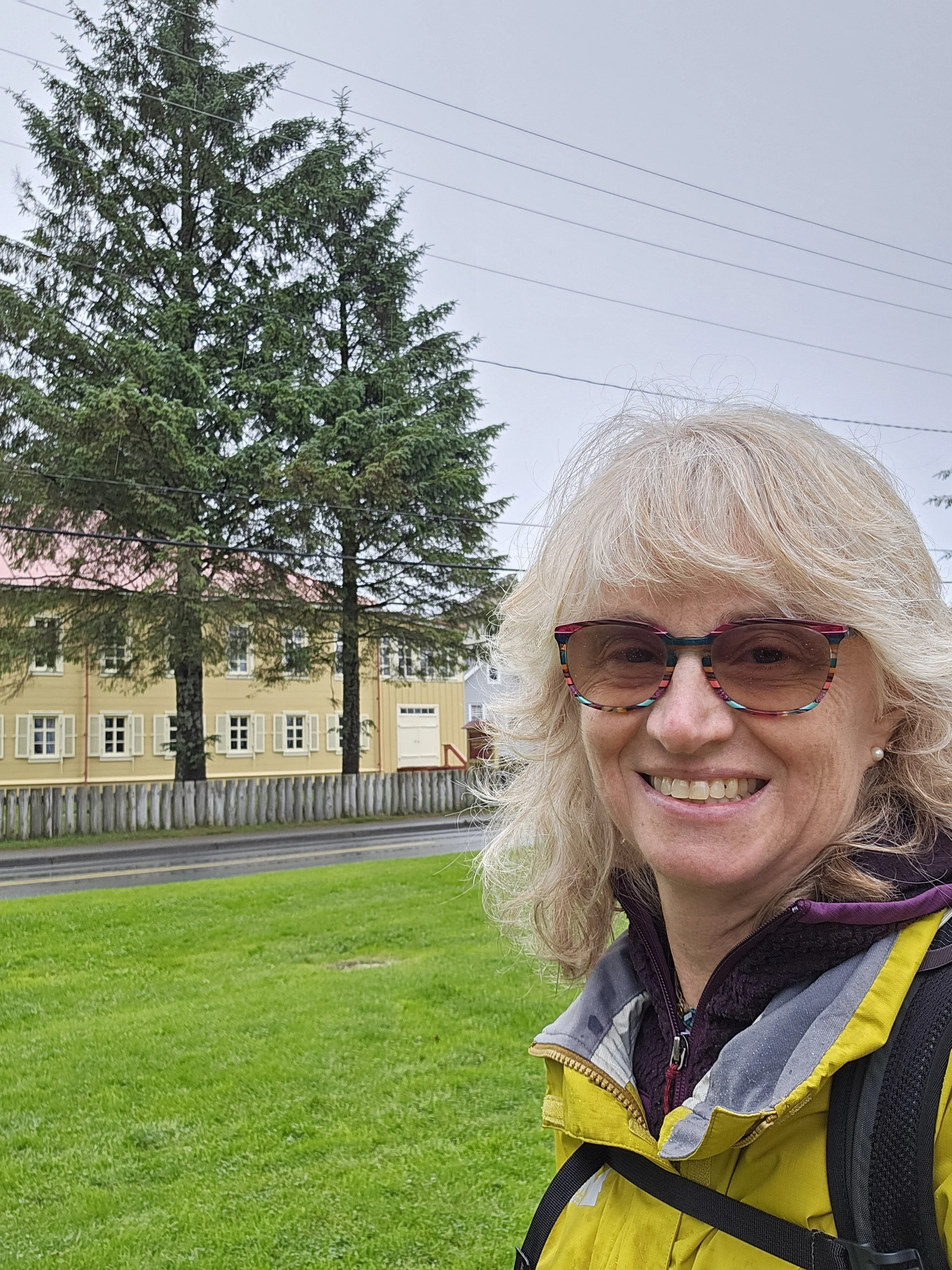 Woman outside smiling in front of yellow building