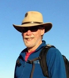 Mike smiling with tan cowboy hat on outside in sushine