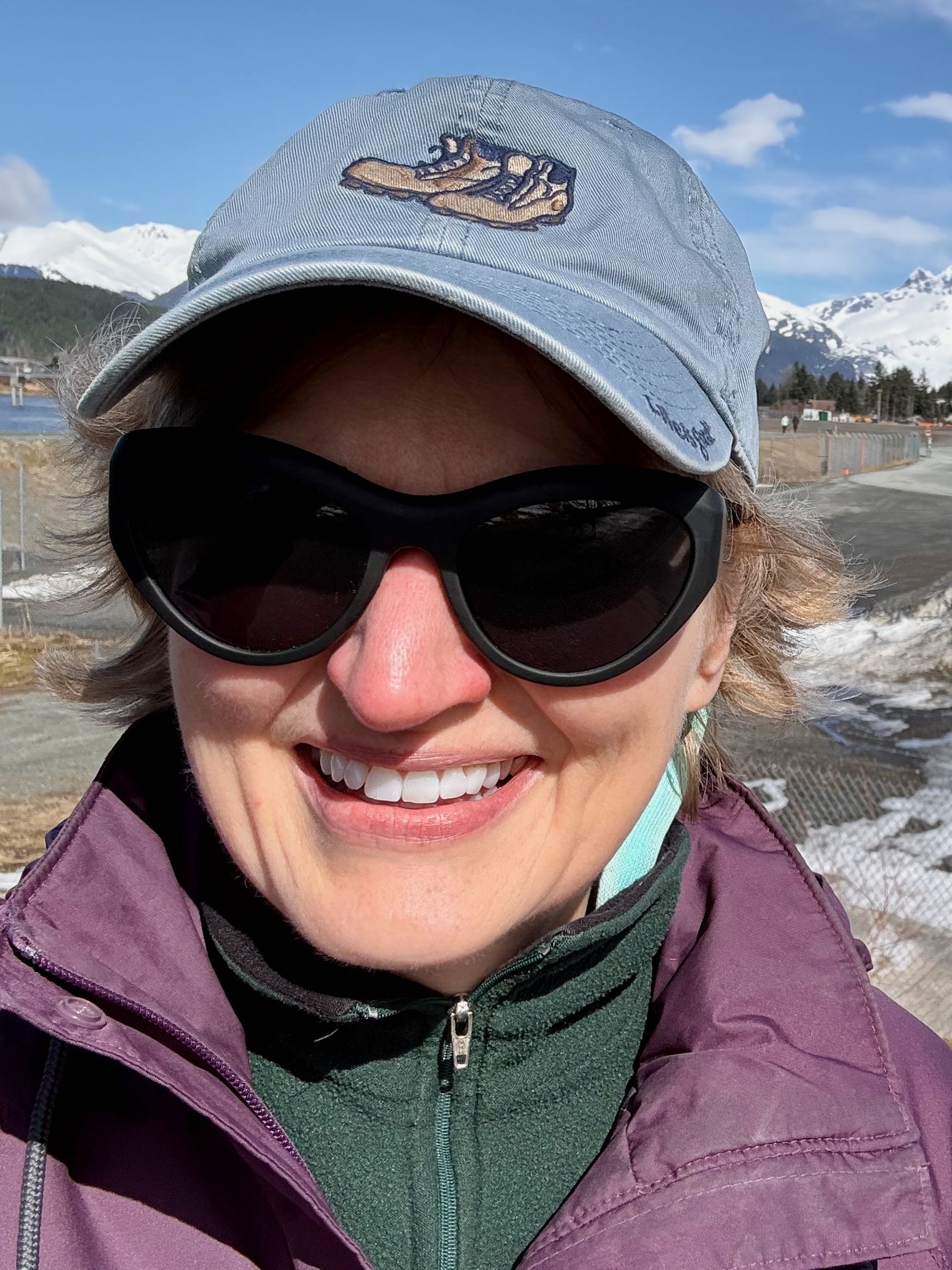Woman smiling outside with sunglasses and hat on