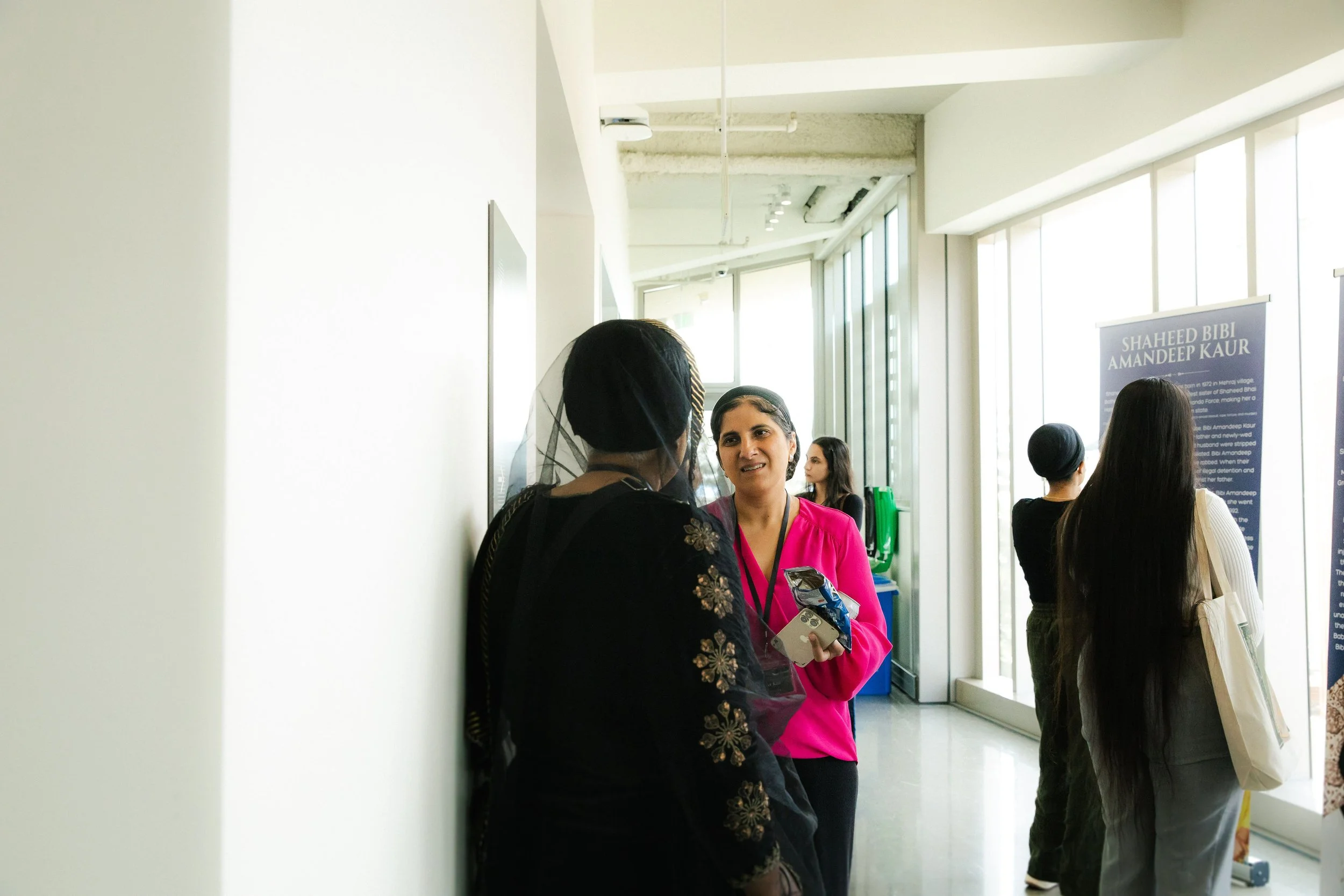A group of women talking in a modern, well-lit indoor space with large windows and informational posters.