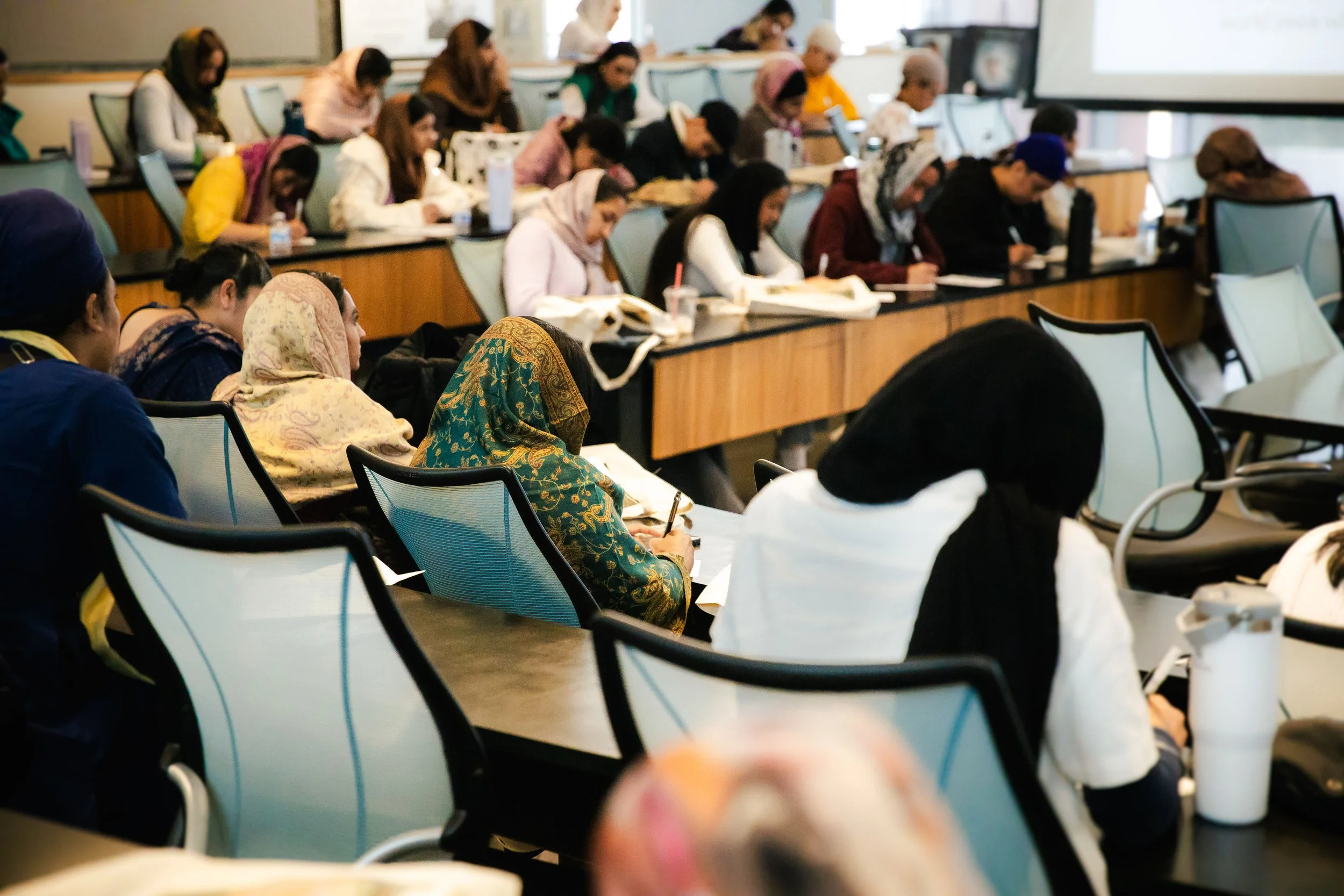 Conference room filled with diverse women taking notes during a seminar.