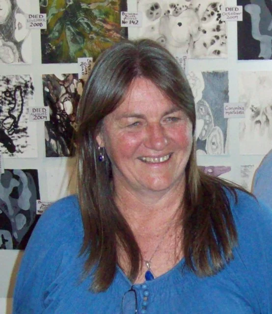 A woman with long brown hair wearing a blue top, smiling, with a background of scientific illustrations and photographs of various species.