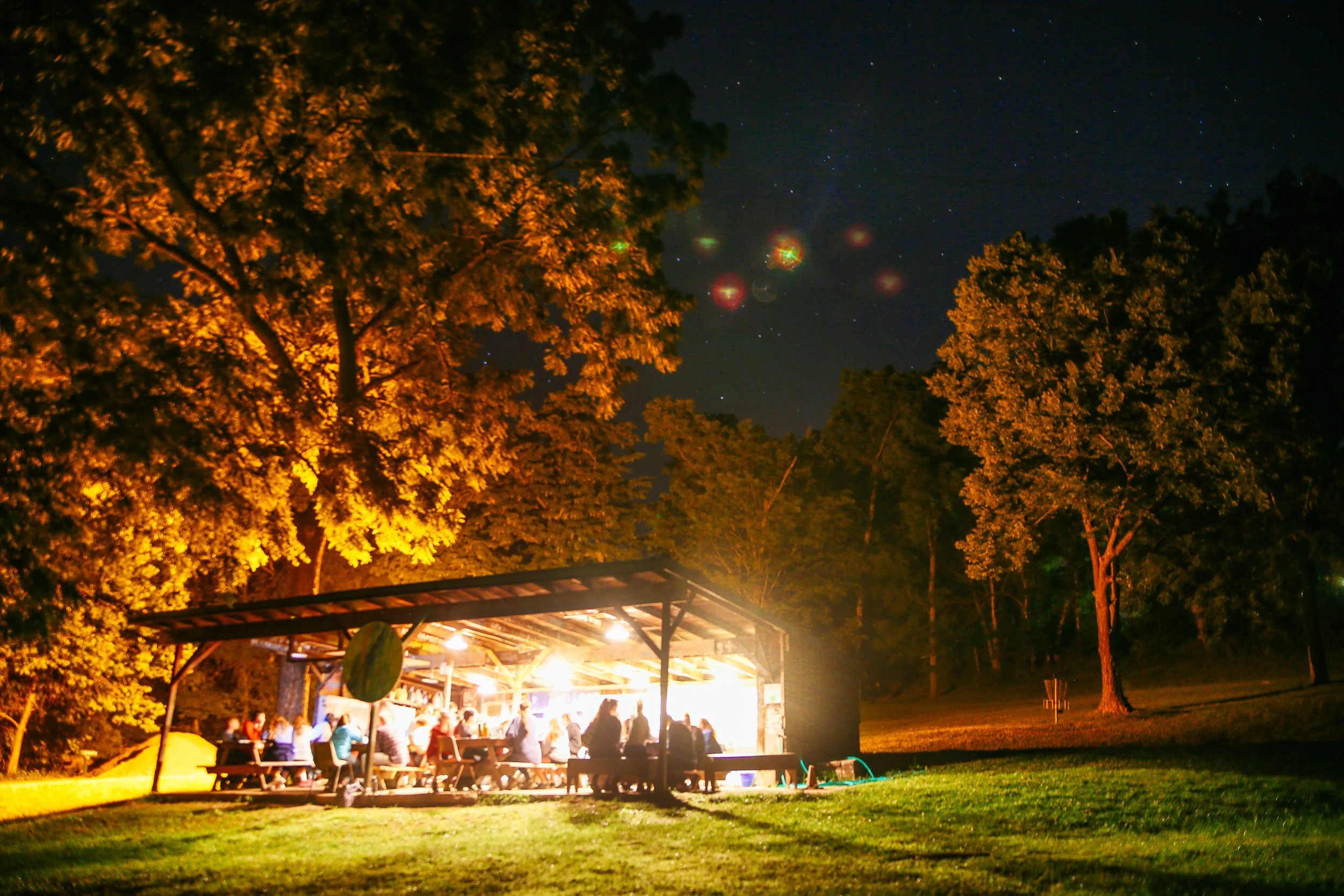 Heartland Christian Camp Paid Gap Year Internship Men and Women Sitting Together Outside at night under lights in a forest Near Kansas City, Missouri