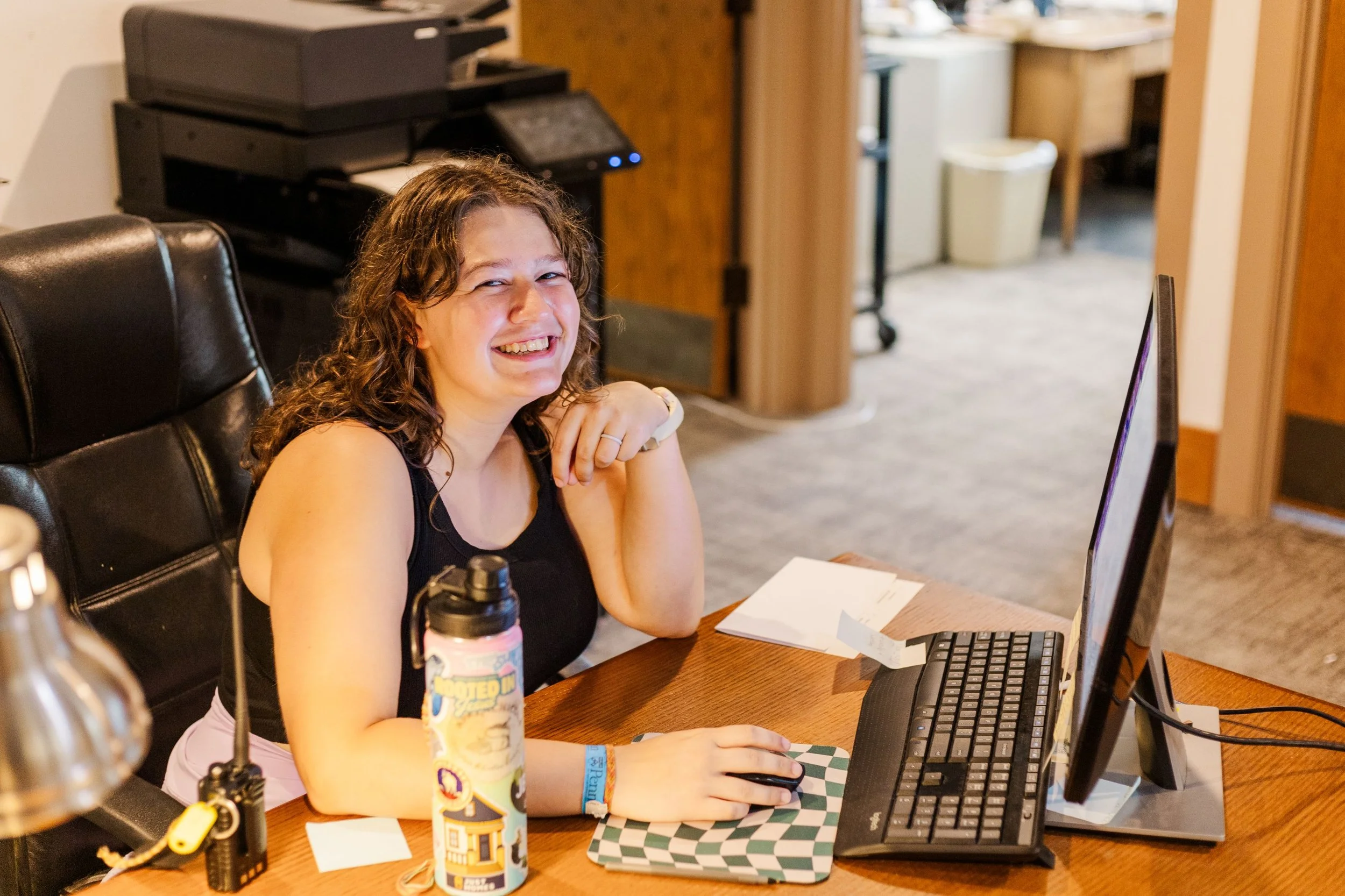 Heartland Christian Camp Paid Gap Year Internship woman working in an office on a computer while smiling near Kansas City, Missouri