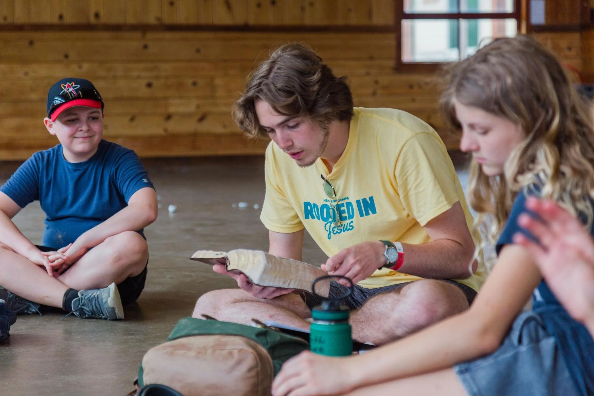 Heartland Christian Camp Paid Gap Year Internship man sitting and reading the Bible to kids  Near Kansas City, Missouri