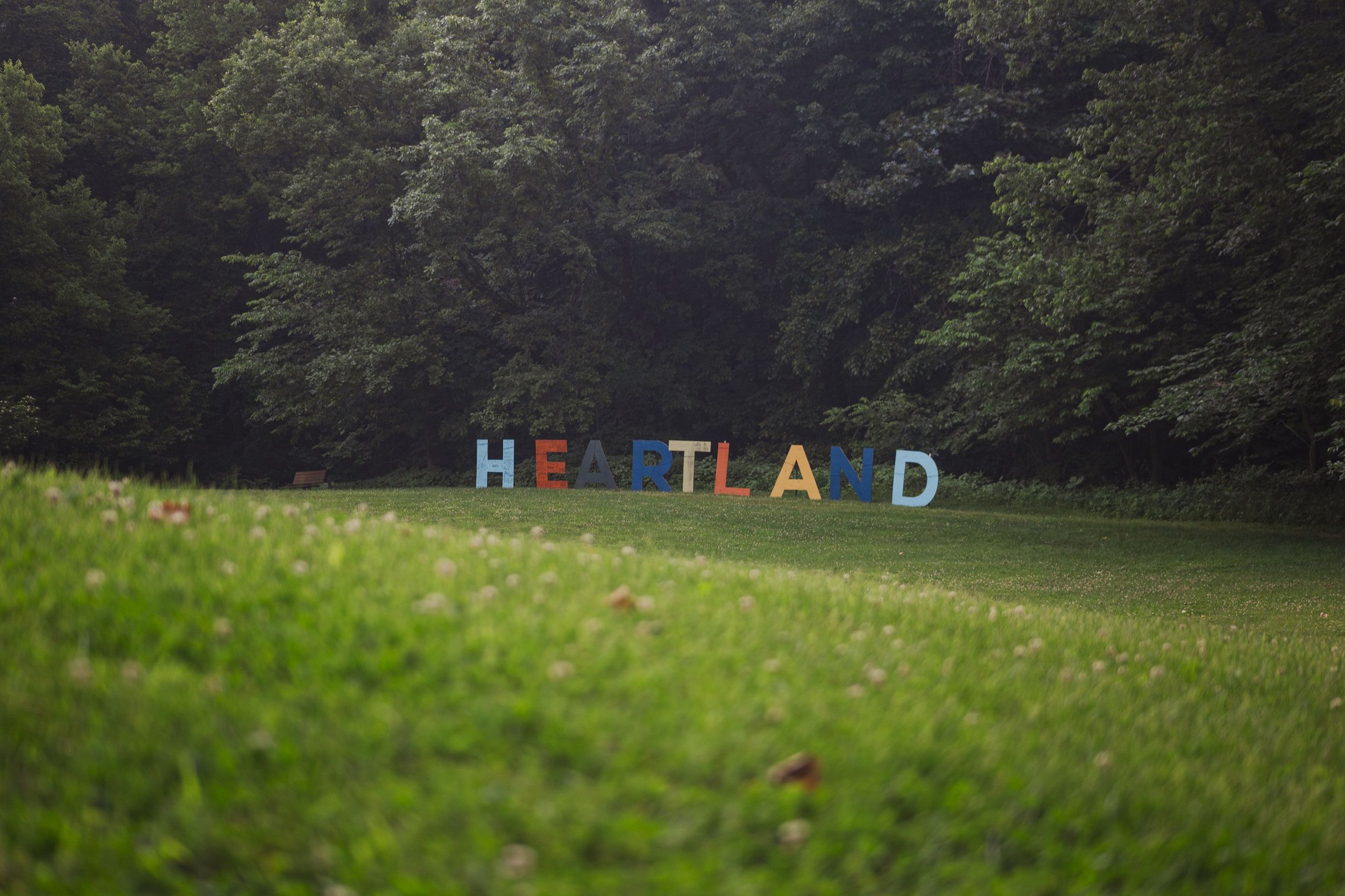 Colorful large letters spelling 'HEARTLAND' on grass at Heartland Christian Camp in Parkville, Missouri near Kansas City with trees in the background.