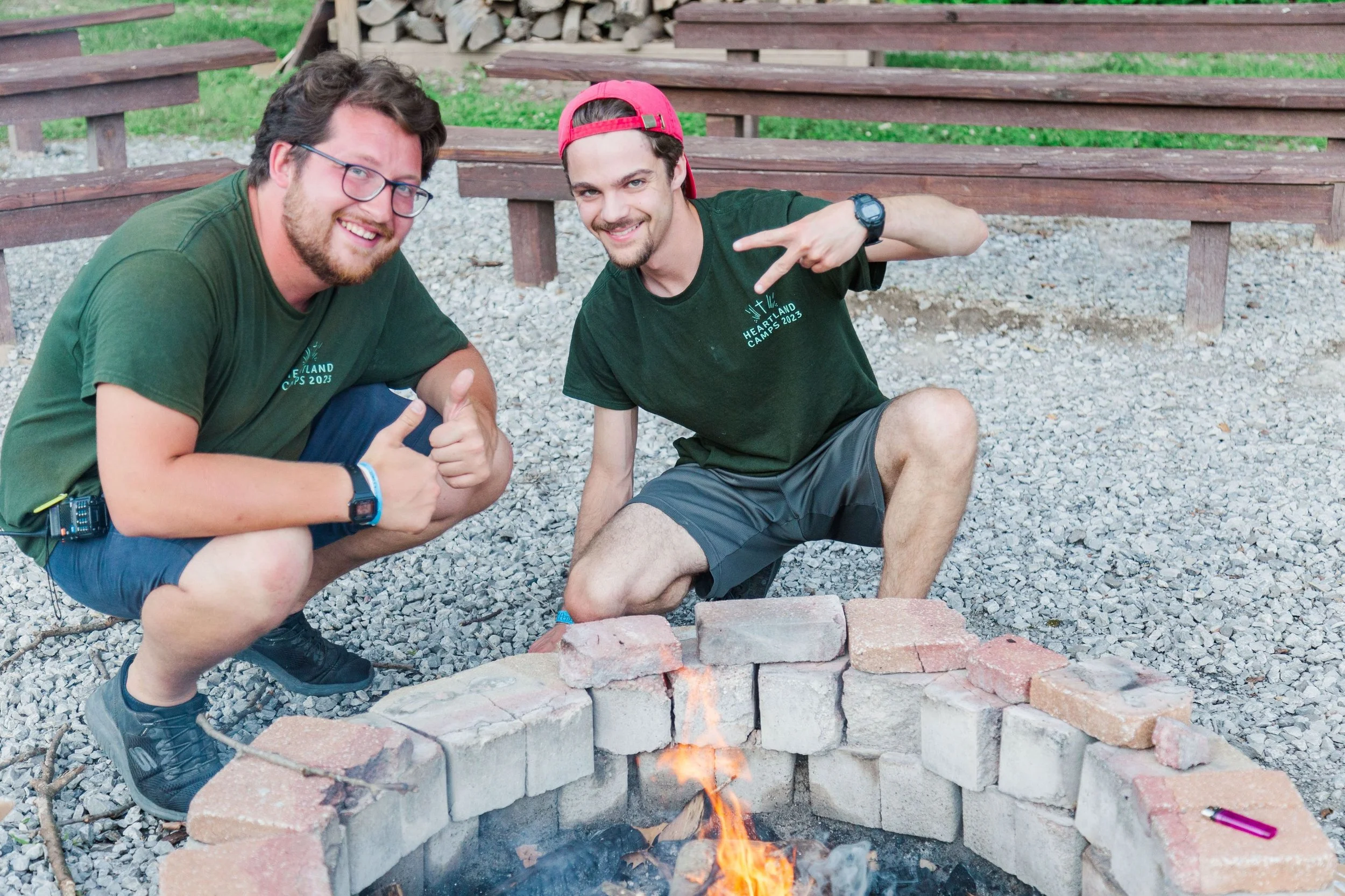 Heartland Christian Camp Paid Gap Year Internship men building a camp fire and smiling together Outside Near Kansas City, Missouri