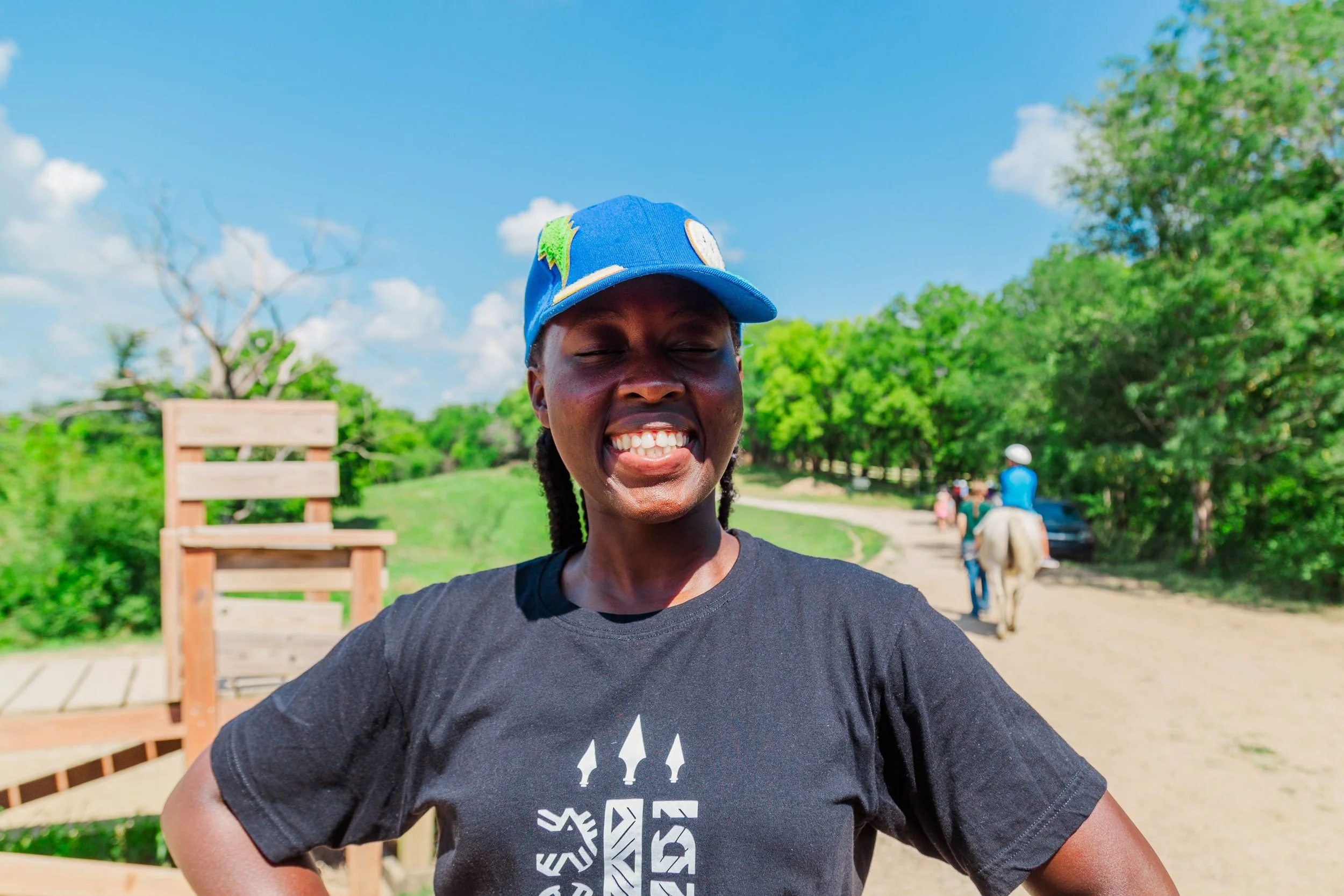 Heartland Christian Camp Paid Gap Year Internship woman standing and smiling near horses Outside Near Kansas City, Missouri