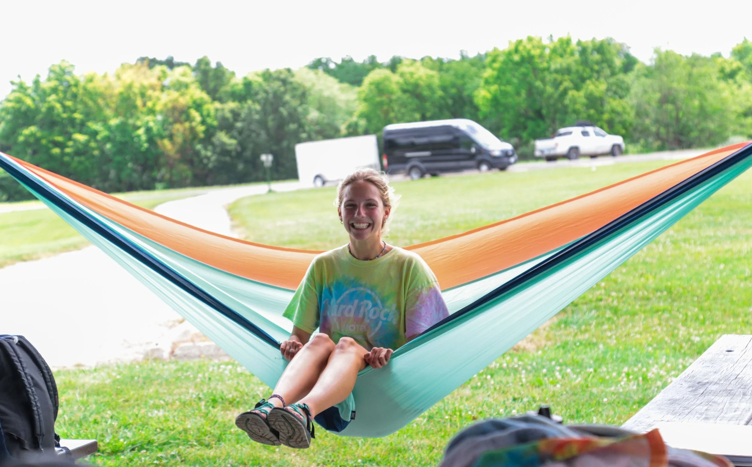 Heartland Christian Camp Paid Gap Year Internship woman sitting in a hammock and smiling Outside Near Kansas City, Missouri