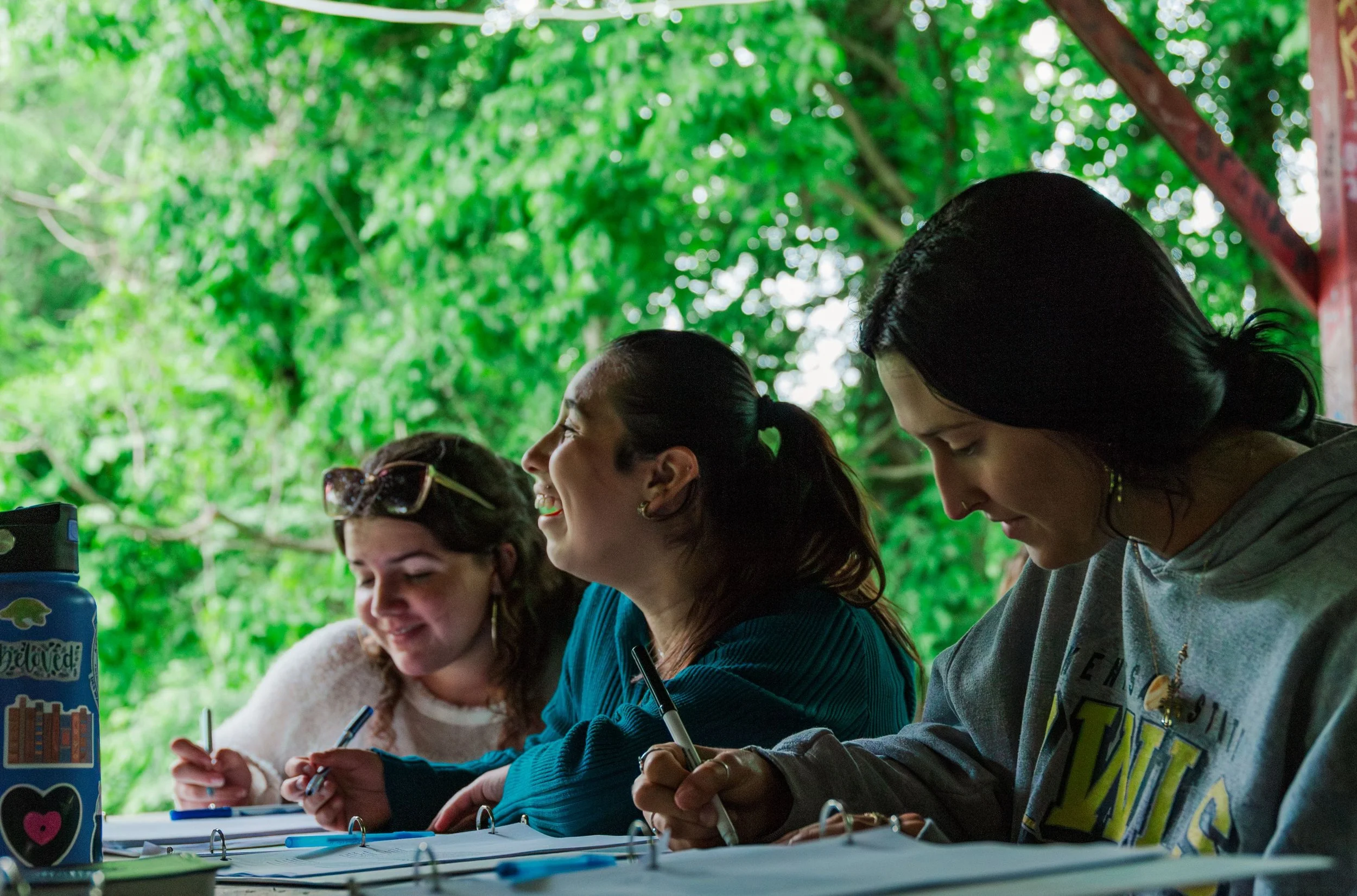 Three women in Heartland Christian Camp Gap Year with pens and journals writing
