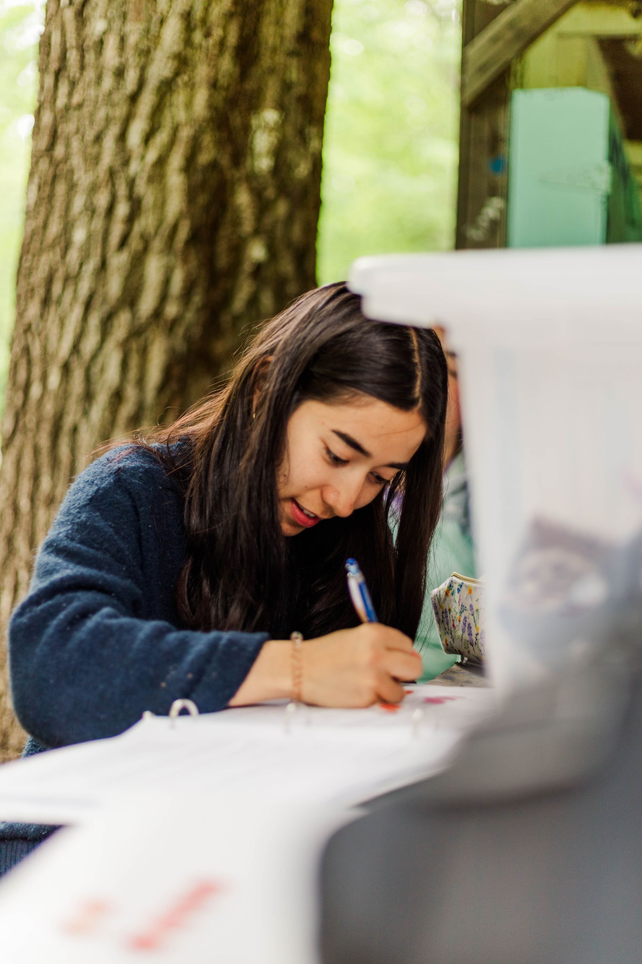 
Heartland Christian Camp Paid Gap Year Internship woman sitting and smiling while writing Outside Near Kansas City, Missouri
