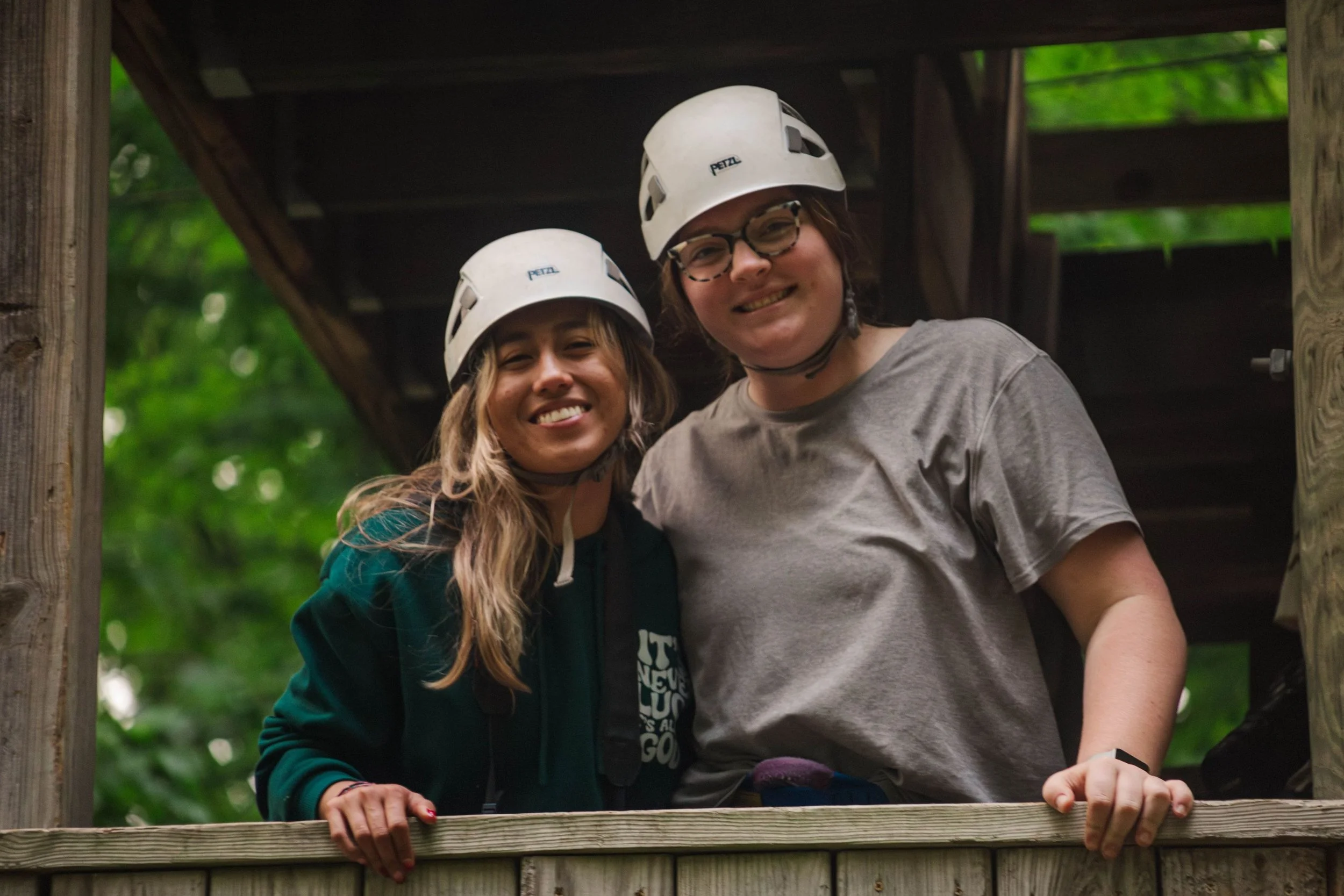 Heartland Christian Camp Paid Gap Year Internship women standing and smiling in helmets on a high ropes course together Outside Near Kansas City, Missouri