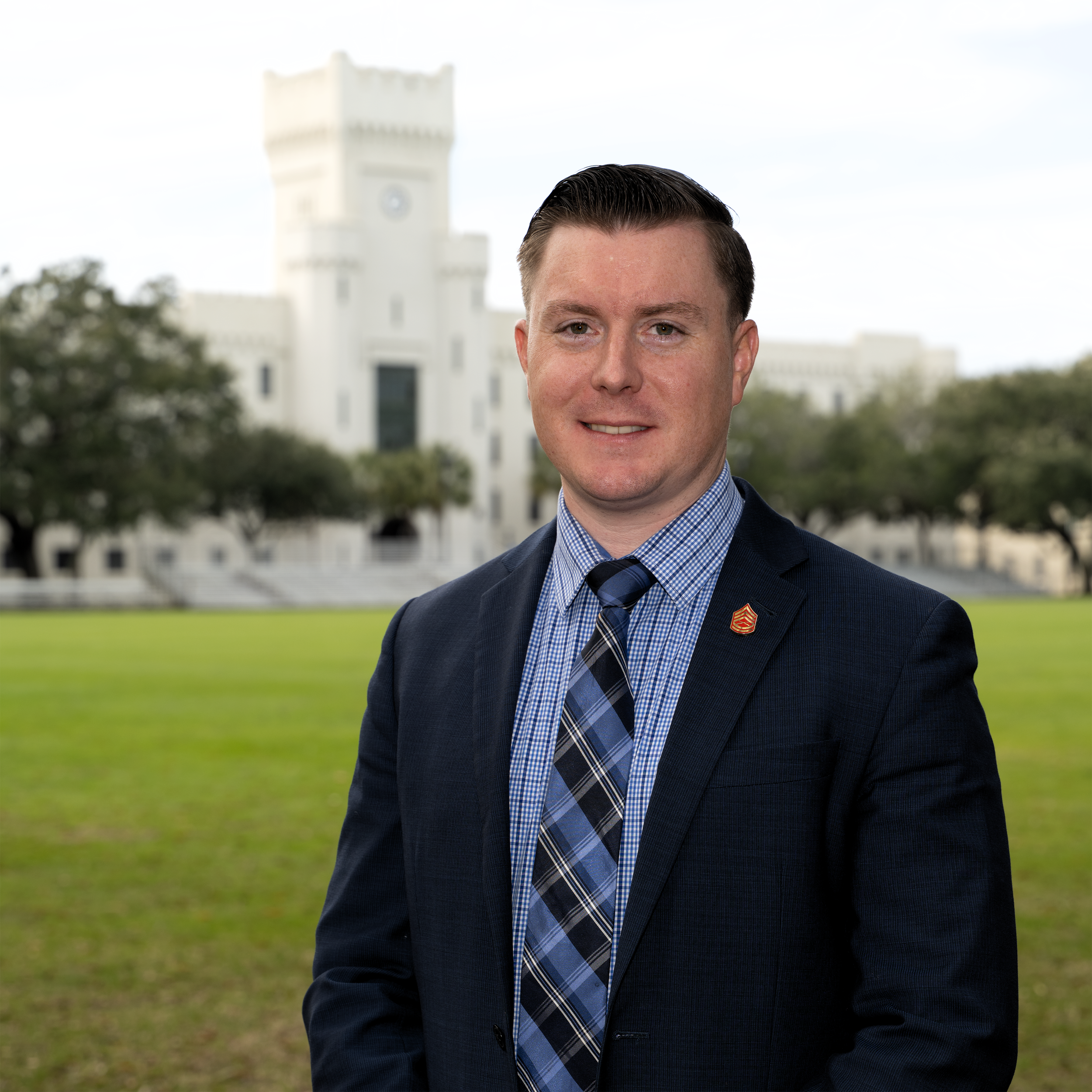 A young man in a dark blazer and shirt standing outdoors near the Reflecting Pool on the National Mall in Washington, D.C., with the Washington Monument in the background.