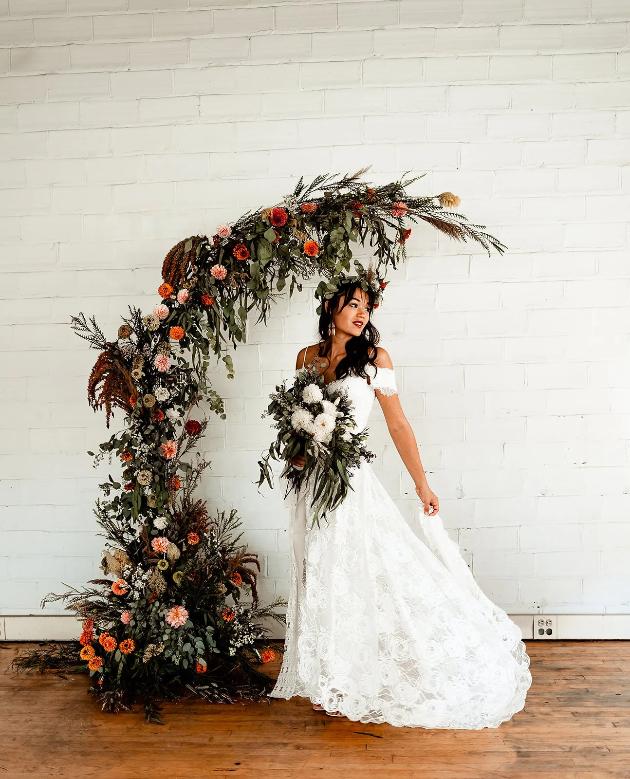 Bride by a Floral Arch with Bouquet