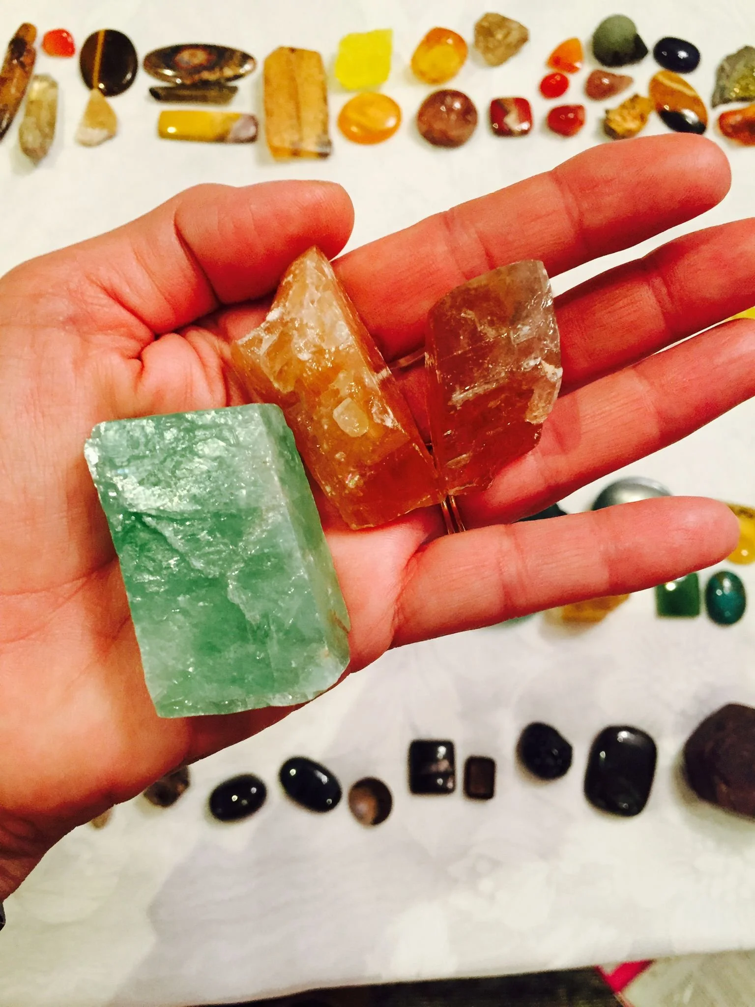 Hand holding one green and two orange crystals.