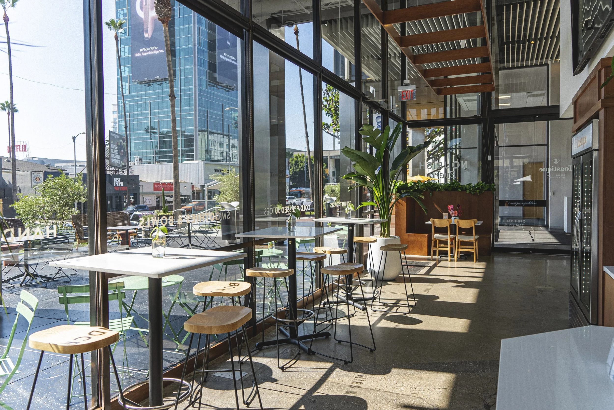 Sunlit interior of Toastique on Sunset with floor-to-ceiling windows, cafe tables and stools on Sunset Blvd in Los Angeles