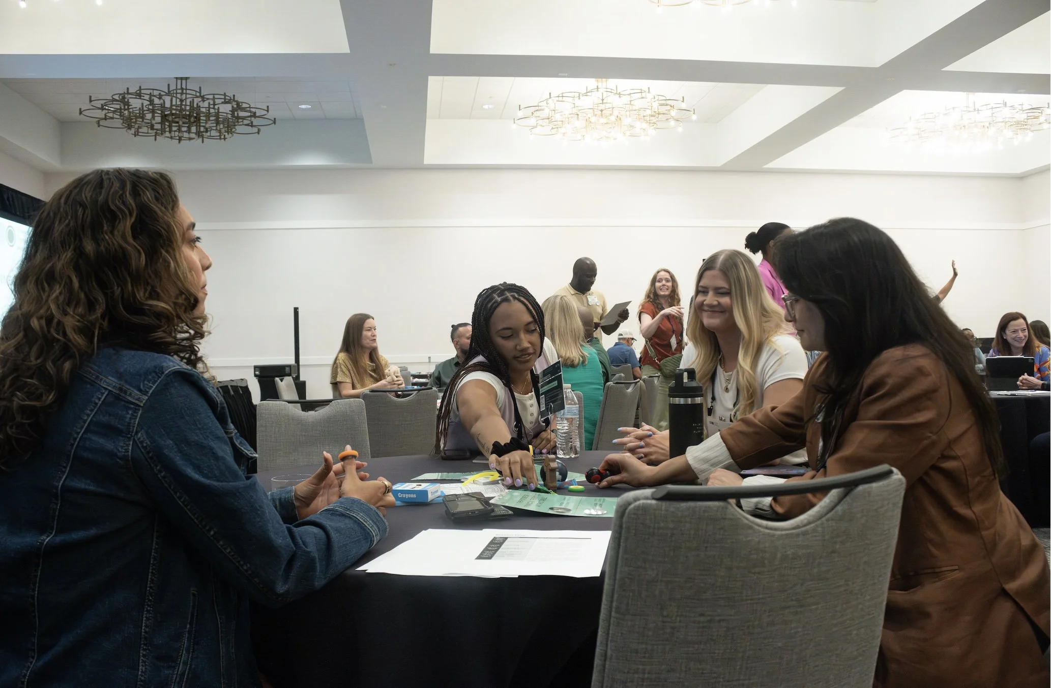 A group of conference attendees interacting and collaborating around a table during an engaging workshop session at the Financial Therapy Association conference.