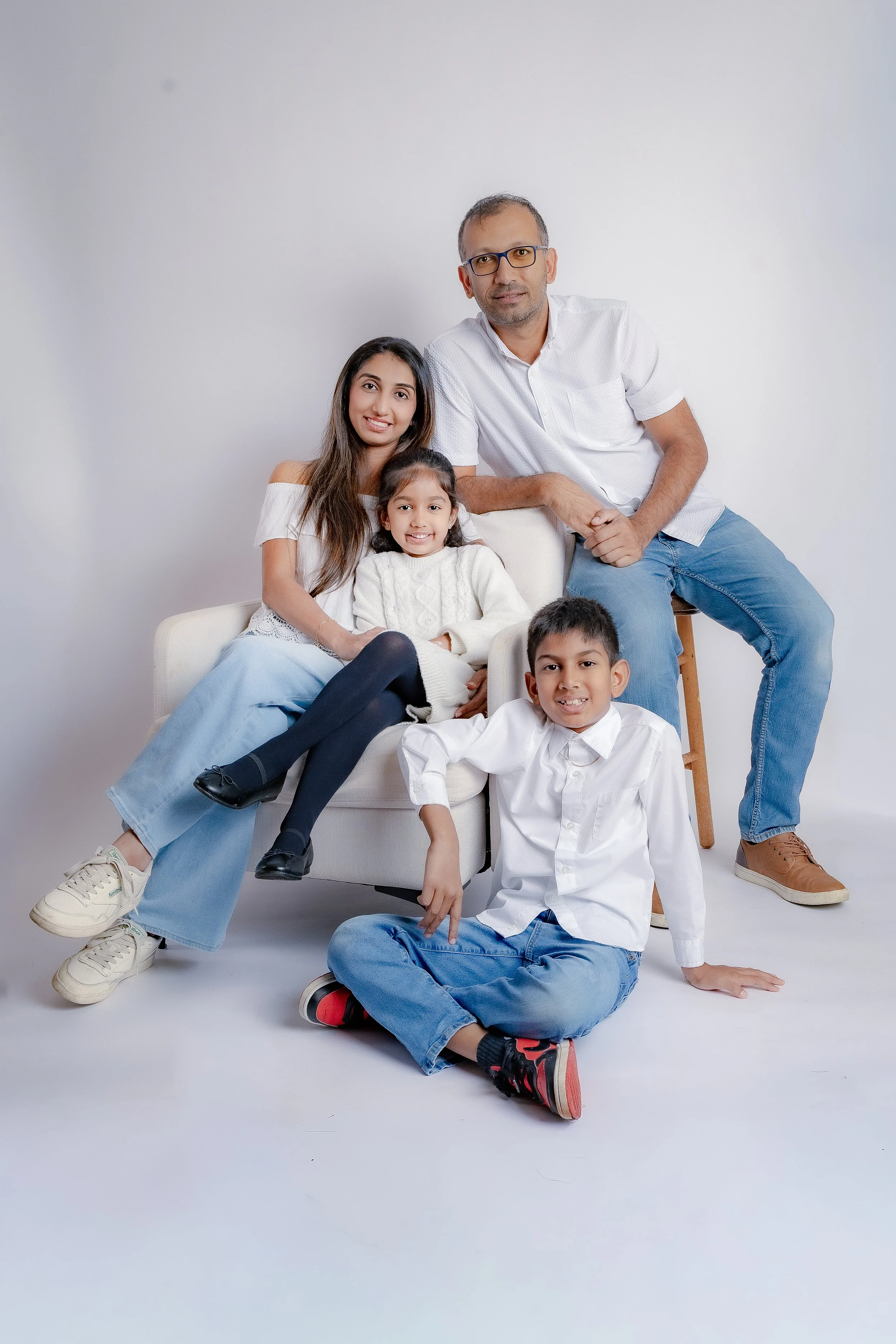 Family portrait with father, mother, and three children against white background. 