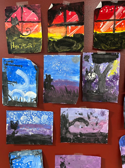 Collection of children's paintings depicting various scenes, including sunsets, trees, moonlit landscapes, and night skies, arranged on a red display board.