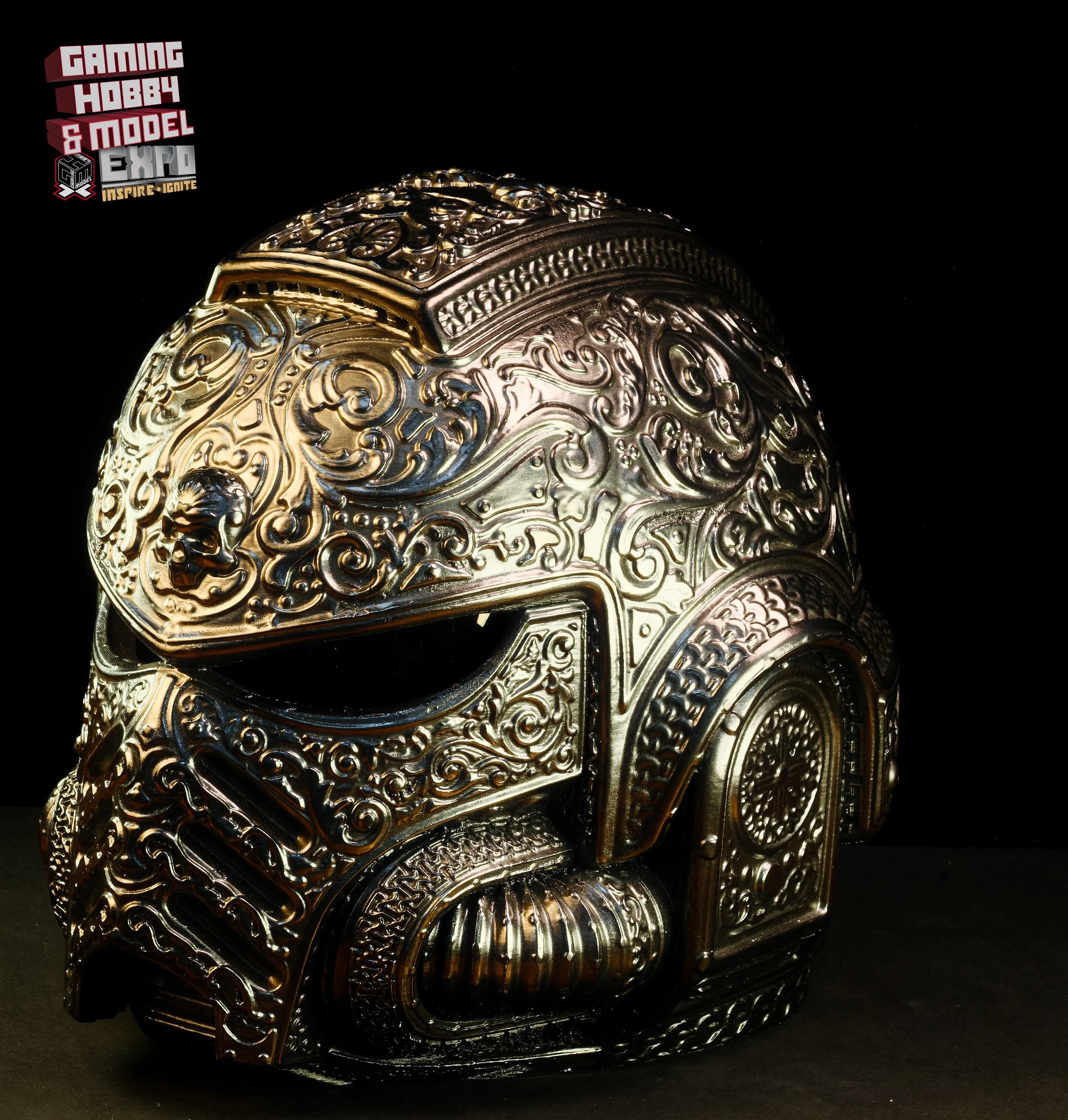 A metallic, intricately designed helmet with ornate carvings and patterns, displayed against a black background.