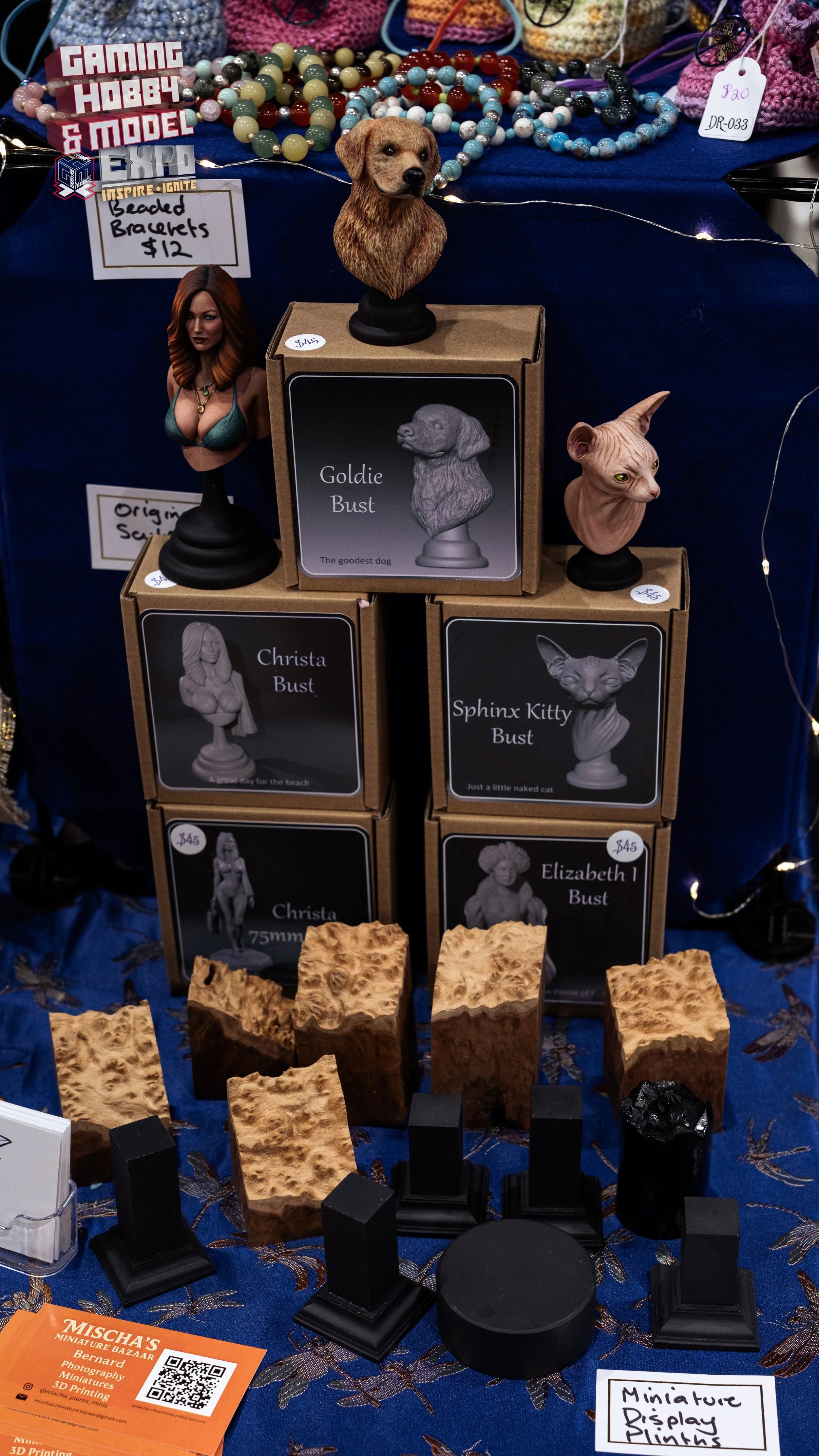 Display of miniature sculptures of dogs and cats, wooden blocks, and jewelry beads at a bazaar stall.