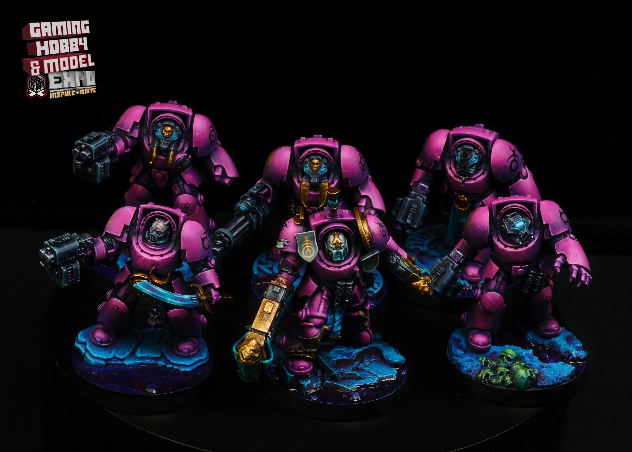 Group of five miniature figurines painted in shades of purple with detailed armor and weapons, set against a dark background with the 