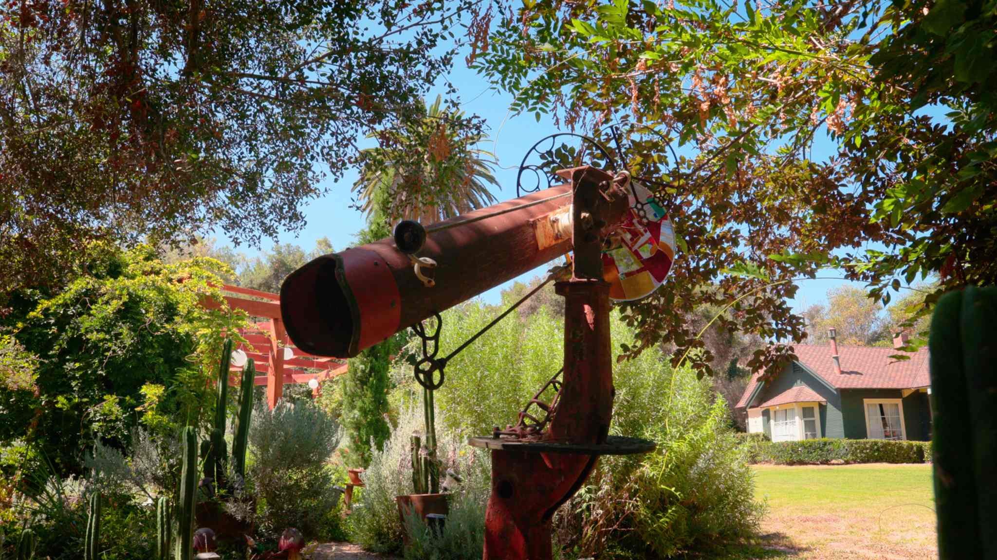Garden with rusted telescope sculpture and house