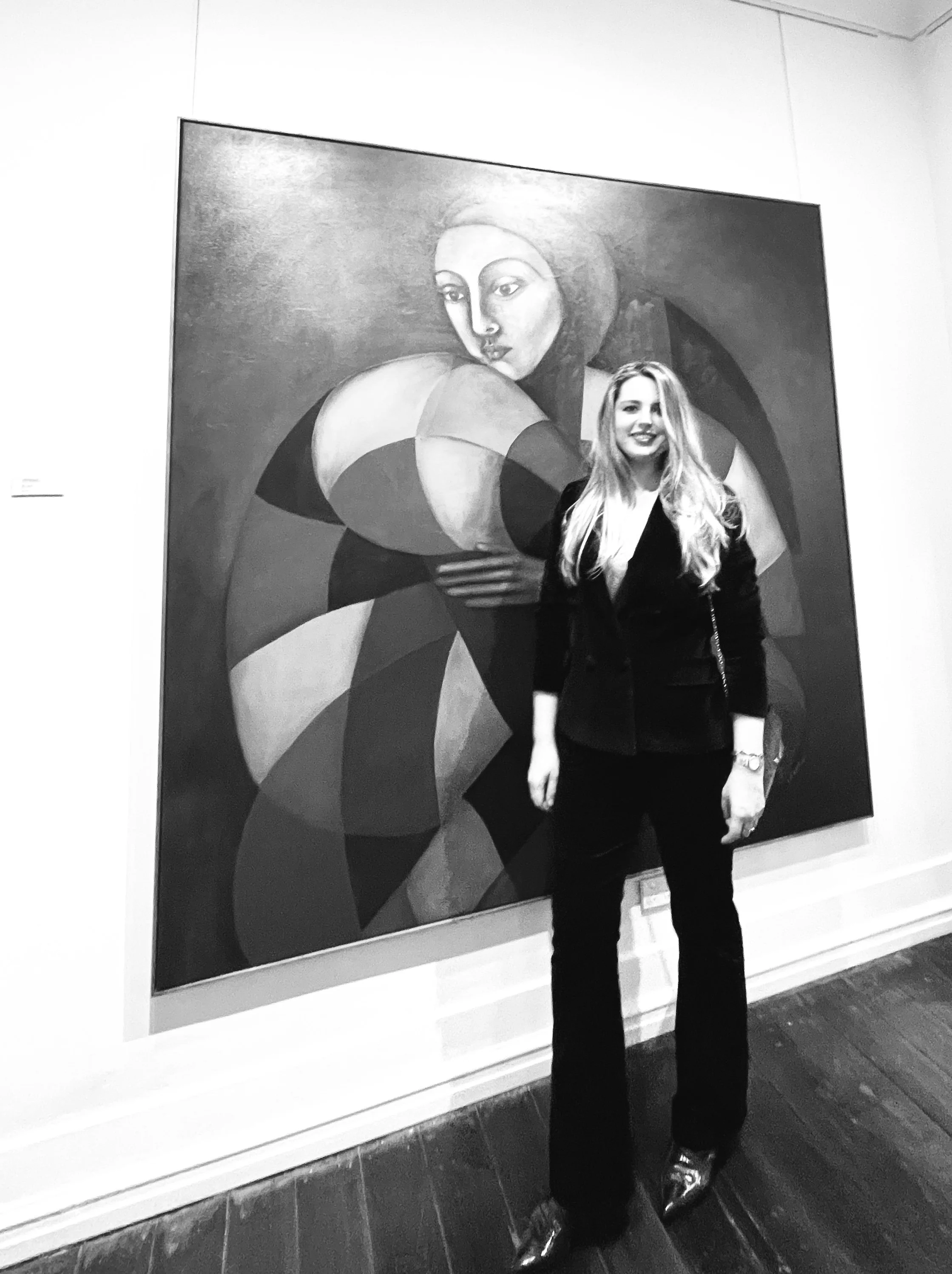 Polish–Australian contemporary artist Iwona Van Niekerk standing beside one of her large-scale geometric figurative oil paintings at an exhibition in Perth, Western Australia.