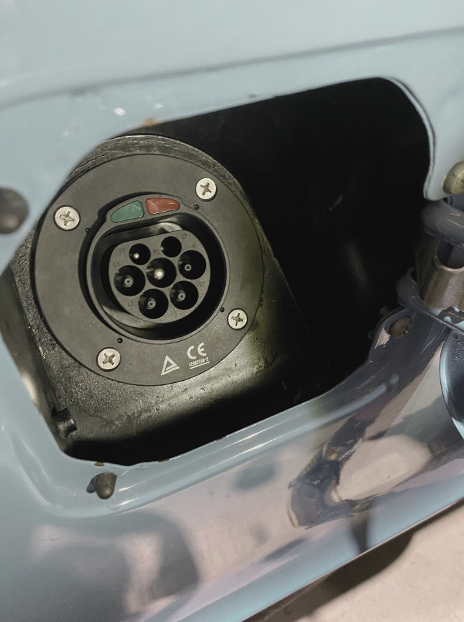 Close-up view of an electric vehicle charging port socket, showing multiple pins and labeled indicators.