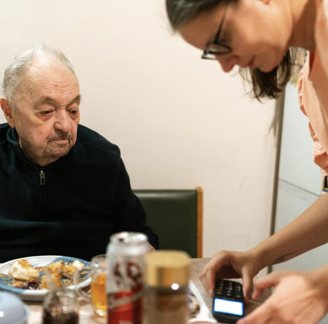 Home care nurse assists elderly man with digital health