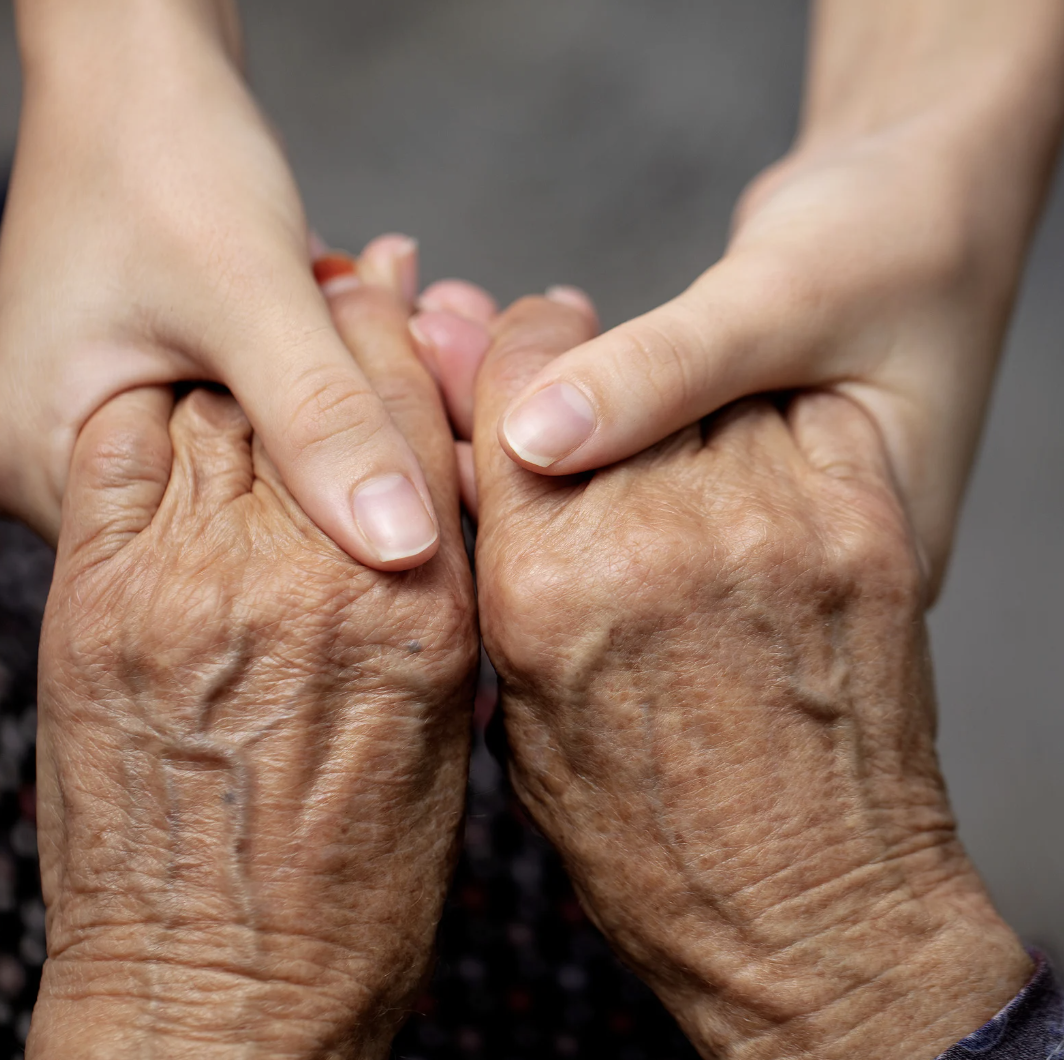 Home care nurse holds hands of elderly woman