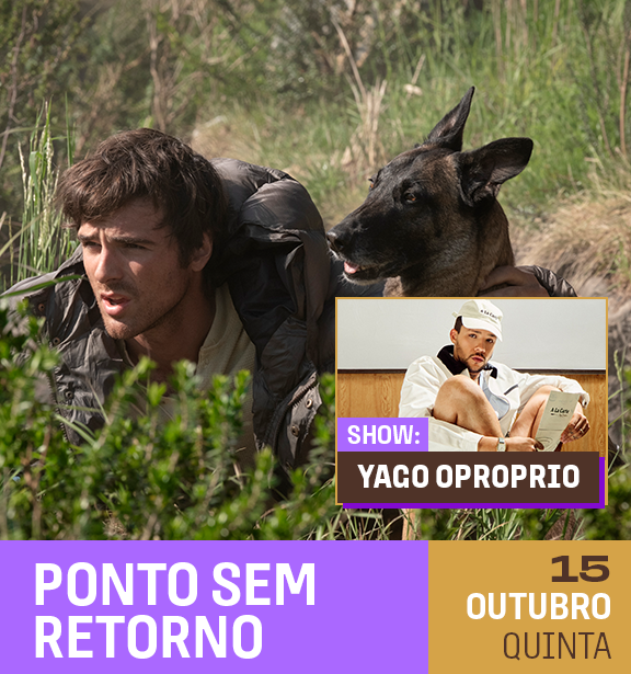 Homem com uma mochila carregada nas costas, rastejando na vegetação, acompanhado por um cachorro preto com orelhas eretas, em um ambiente natural com árvores e arbustos.