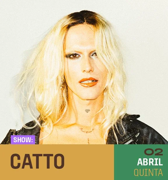 Mulher com cabelo loiro, cabelo bagunçado, usando maquiagem forte e uma jaqueta preta, olhando para frente.