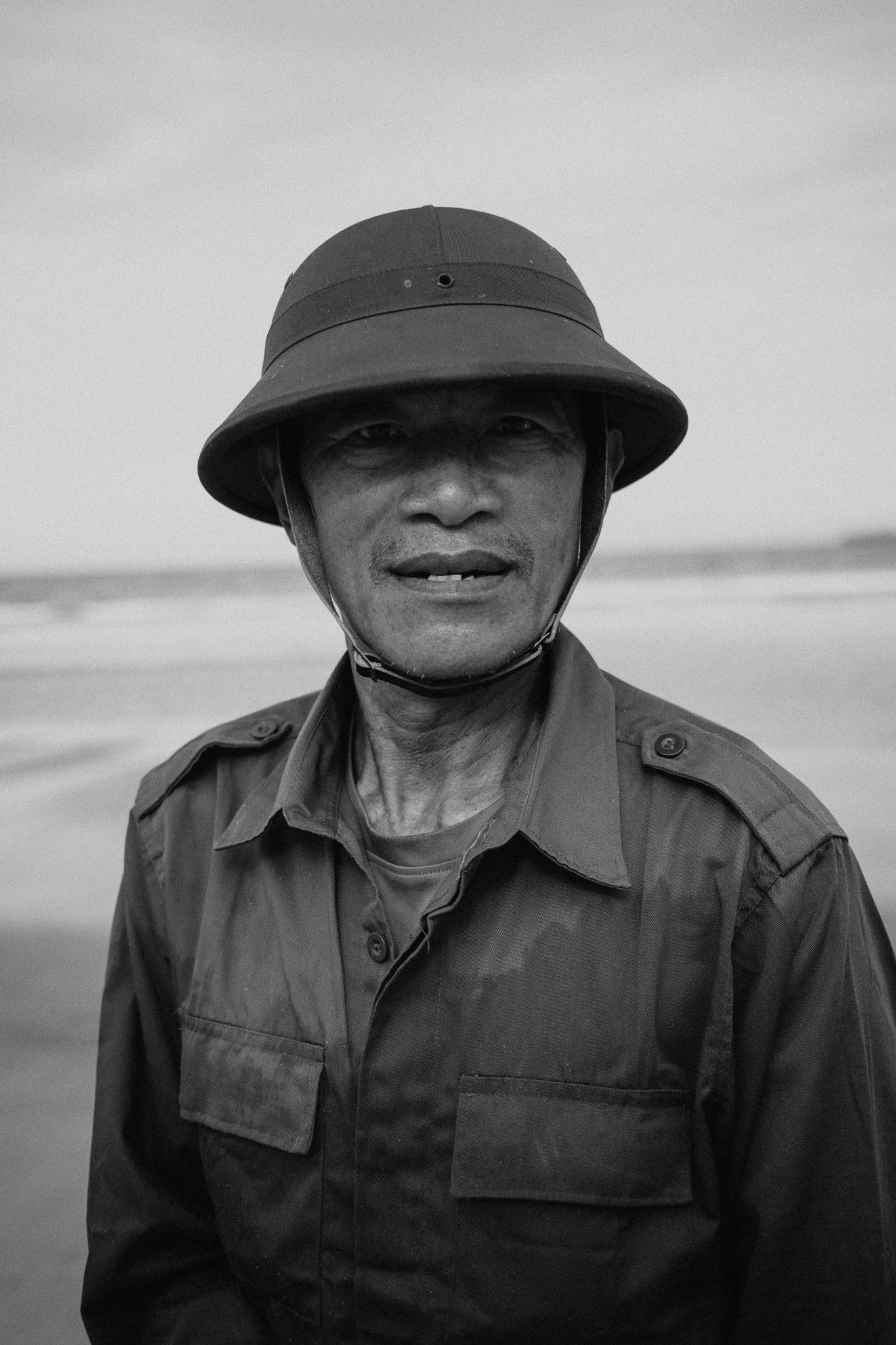 Un homme en uniforme militaire portant un casque sur une plage.