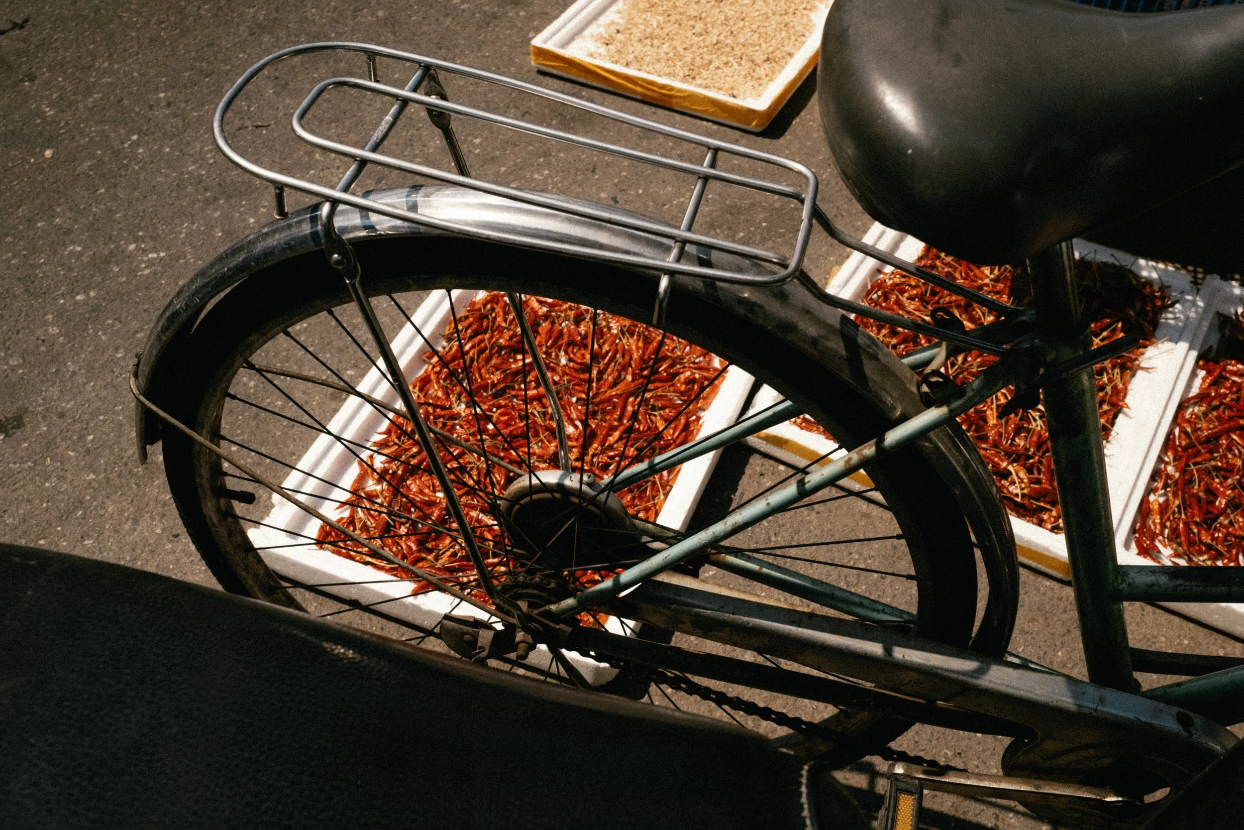 Vélo avec un porte-bagages stationné devant des étals de fruits de mer, probablement des crevettes ou des langoustines, en vente au marché.