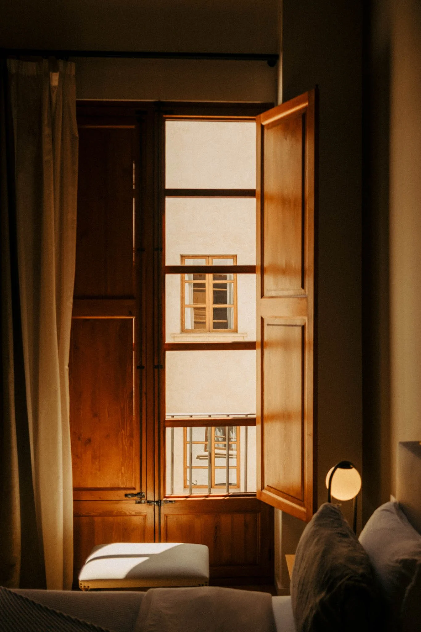Fenêtre en bois ouverte dans une chambre, laissant entrer la lumière naturelle. Mur blanc visible à travers la fenêtre.
