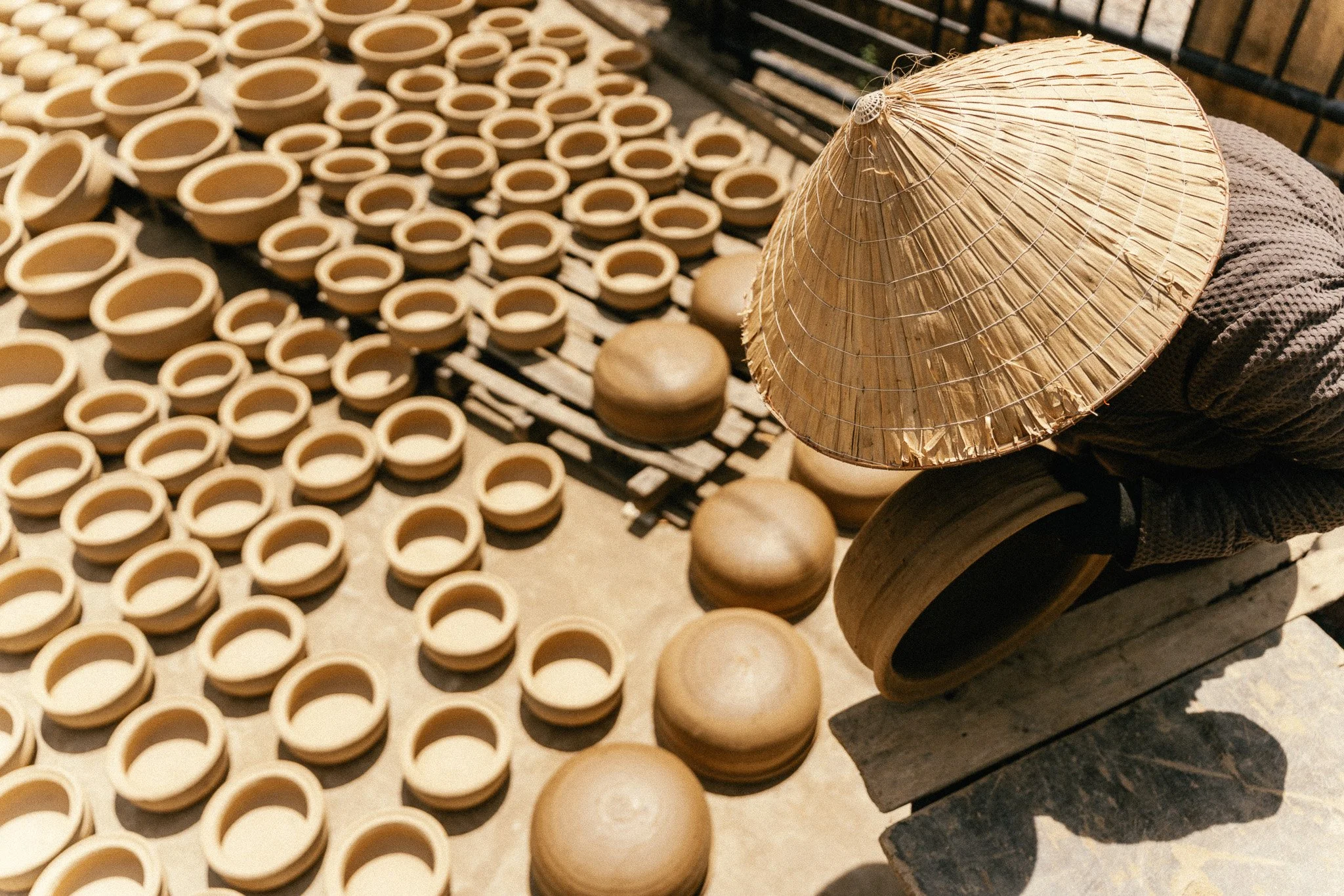 Travail de poterie avec de nombreux petits bols en terre cuite et un chapeau de paille au centre