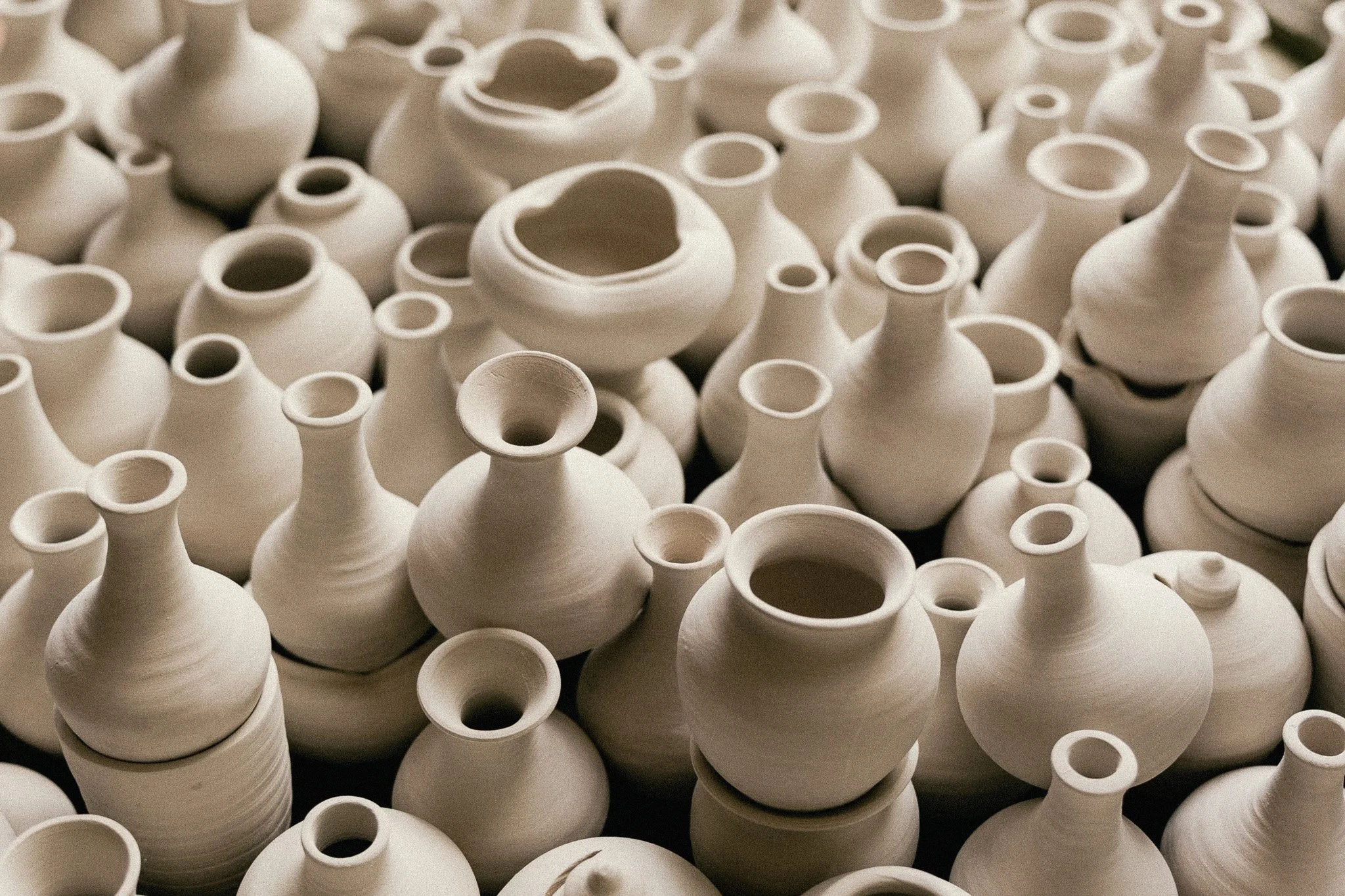 De nombreux vases en céramique blanche empilés et disposés sur une surface.