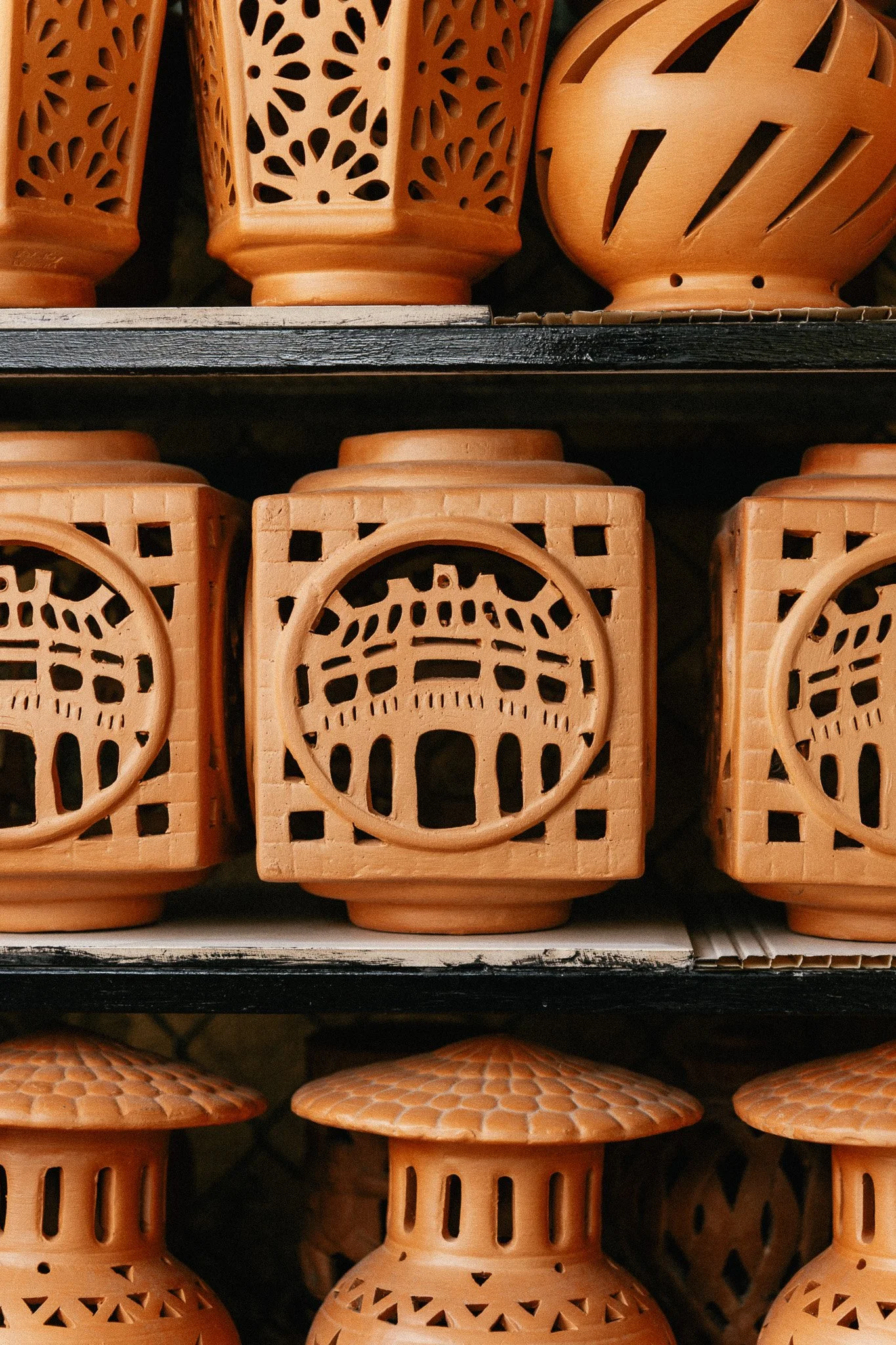 Vases en terre cuite de différentes formes et motifs, disposés sur des étagères.