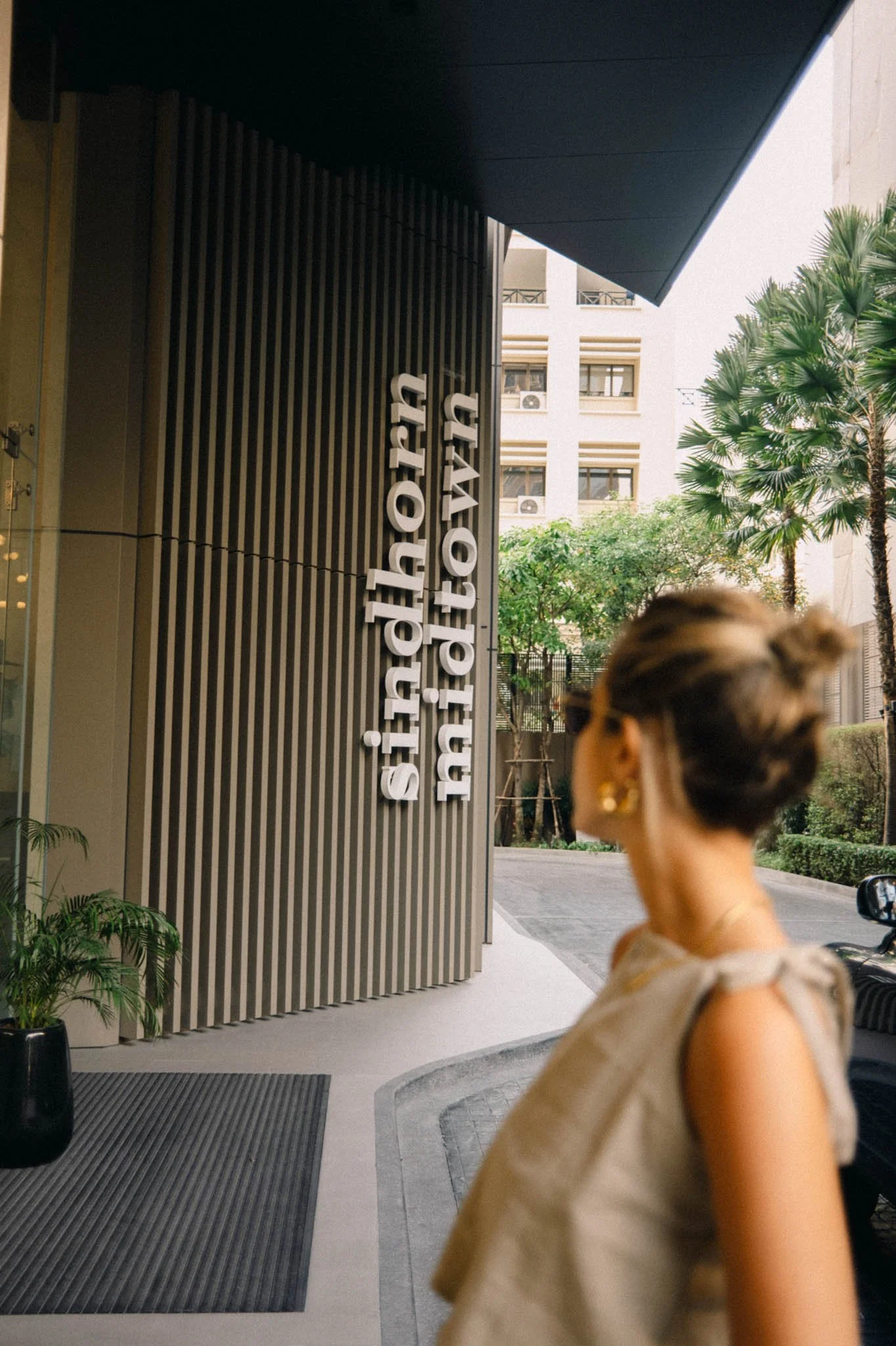 Une femme regarde vers une bâtisse avec un panneau indiquant 'si haut, m.town'.
