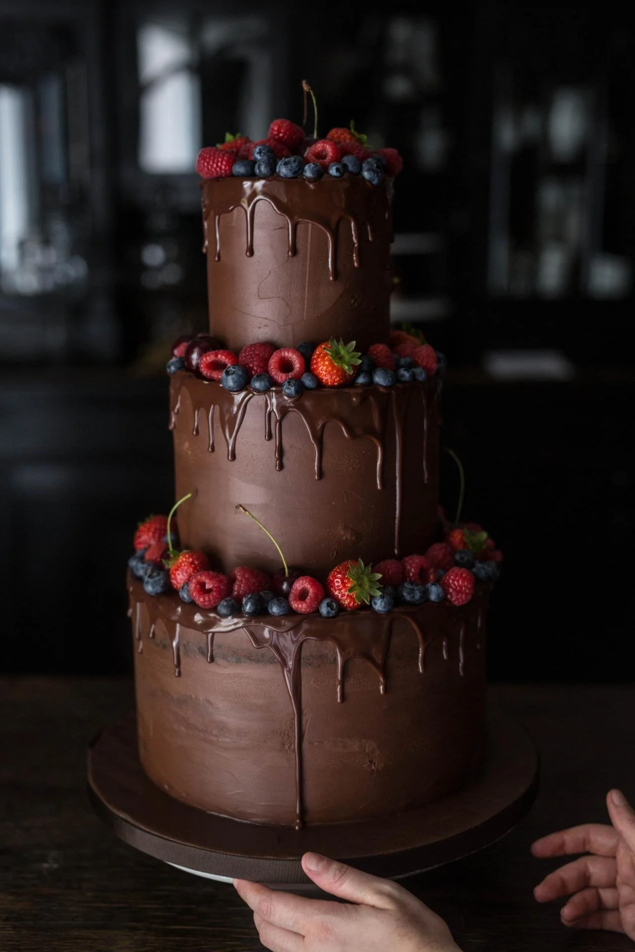 Three-tier chocolate wedding cake with chocolate drip and fresh berries by dilekerei Berlin