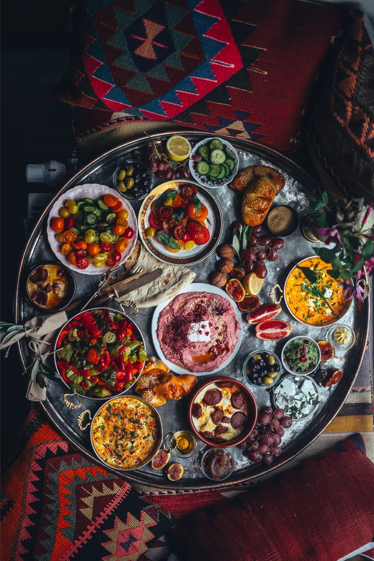 Colorful mezze breakfast selection with dips, olives and seasonal fruit on ornate serving tray