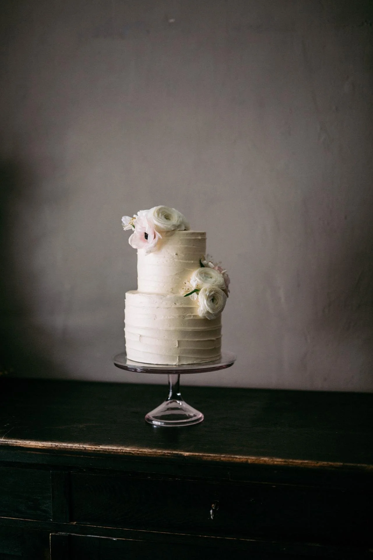 Elegant three-tier white wedding cake with delicate white floral details