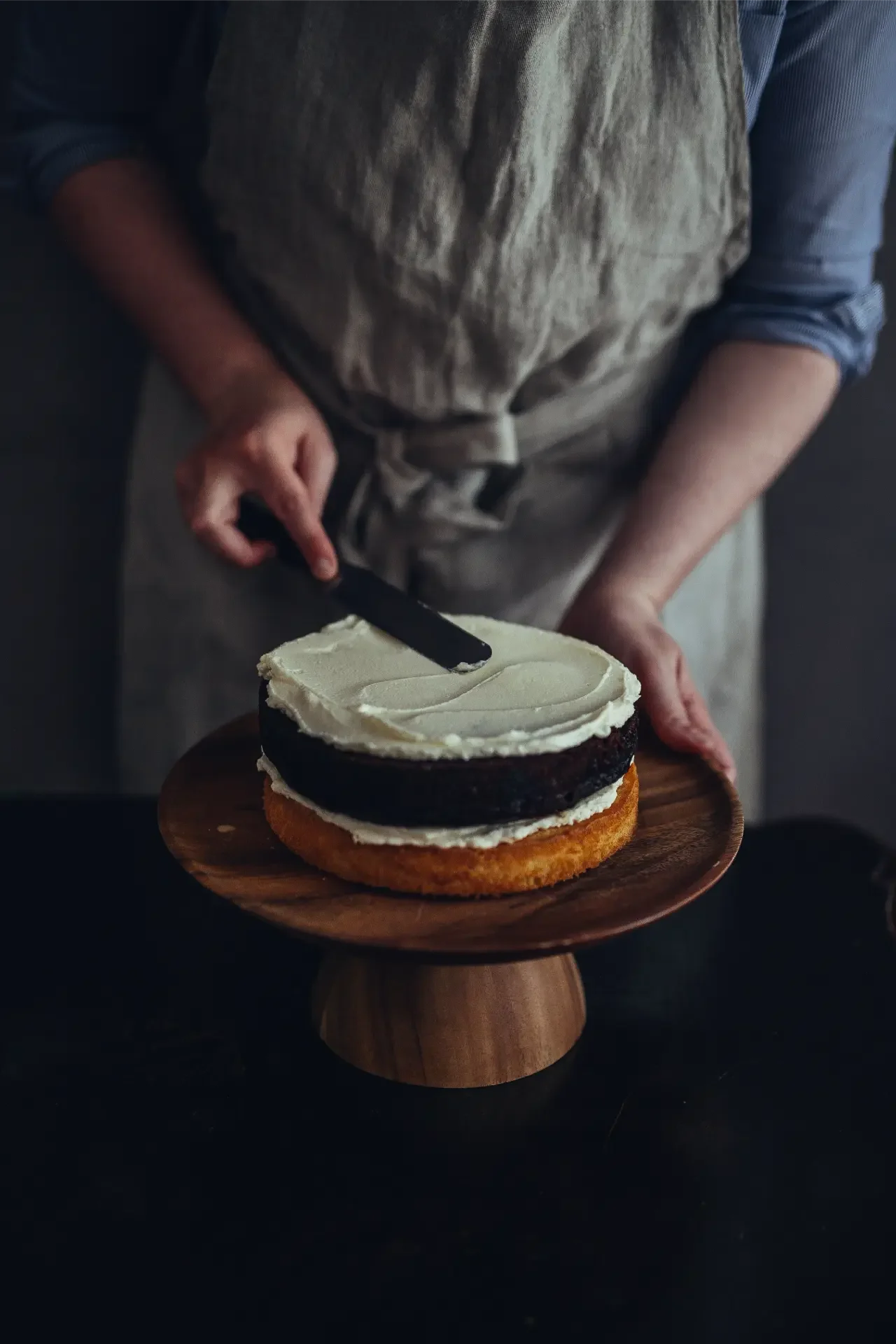 Spreading cream onto tahini layer cake by hand